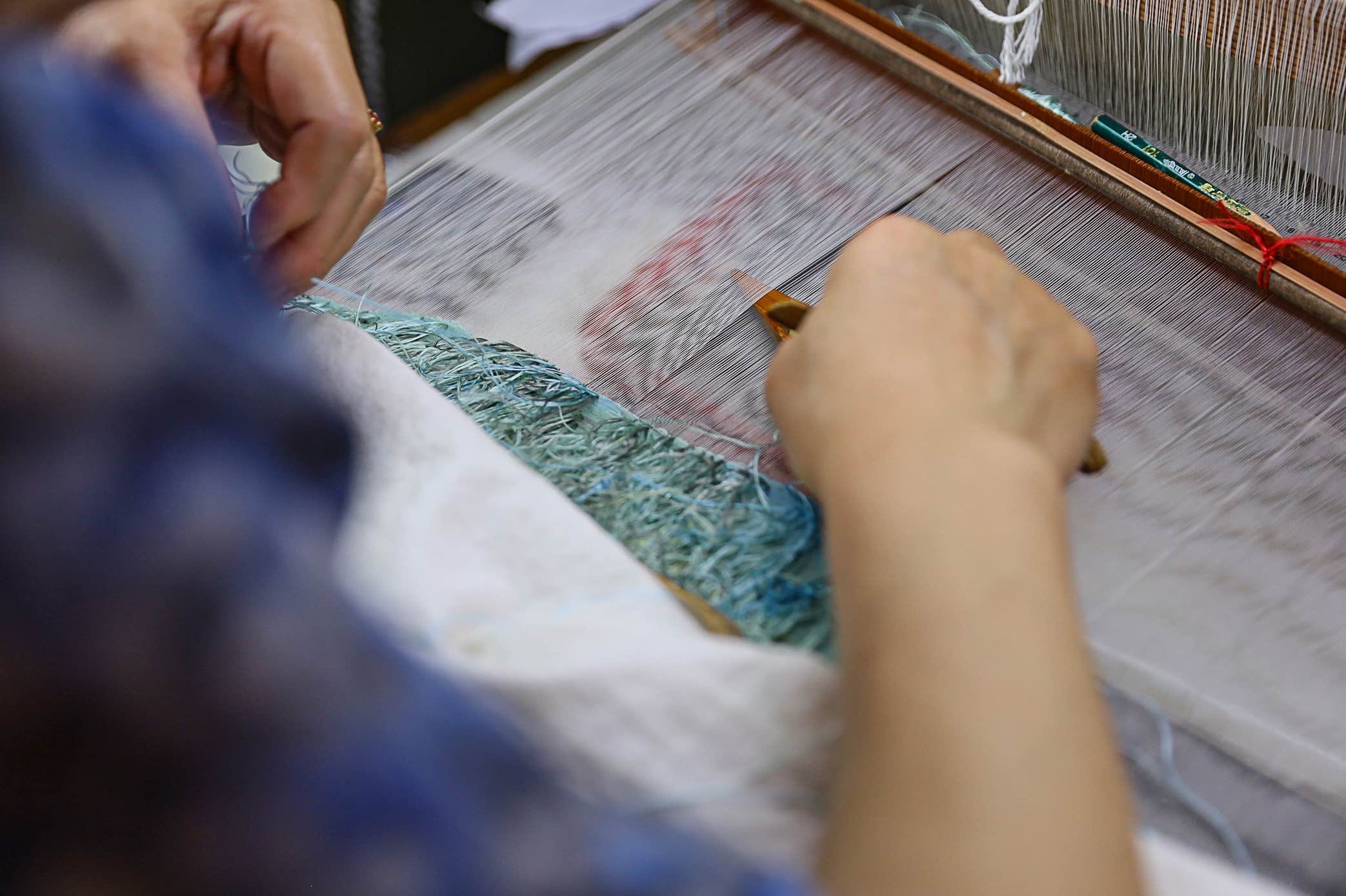 Artisan working on hand embroidery for bespoke Qipao using Shu embroidery technique on silk fabric at JINZA Los Angeles atelier