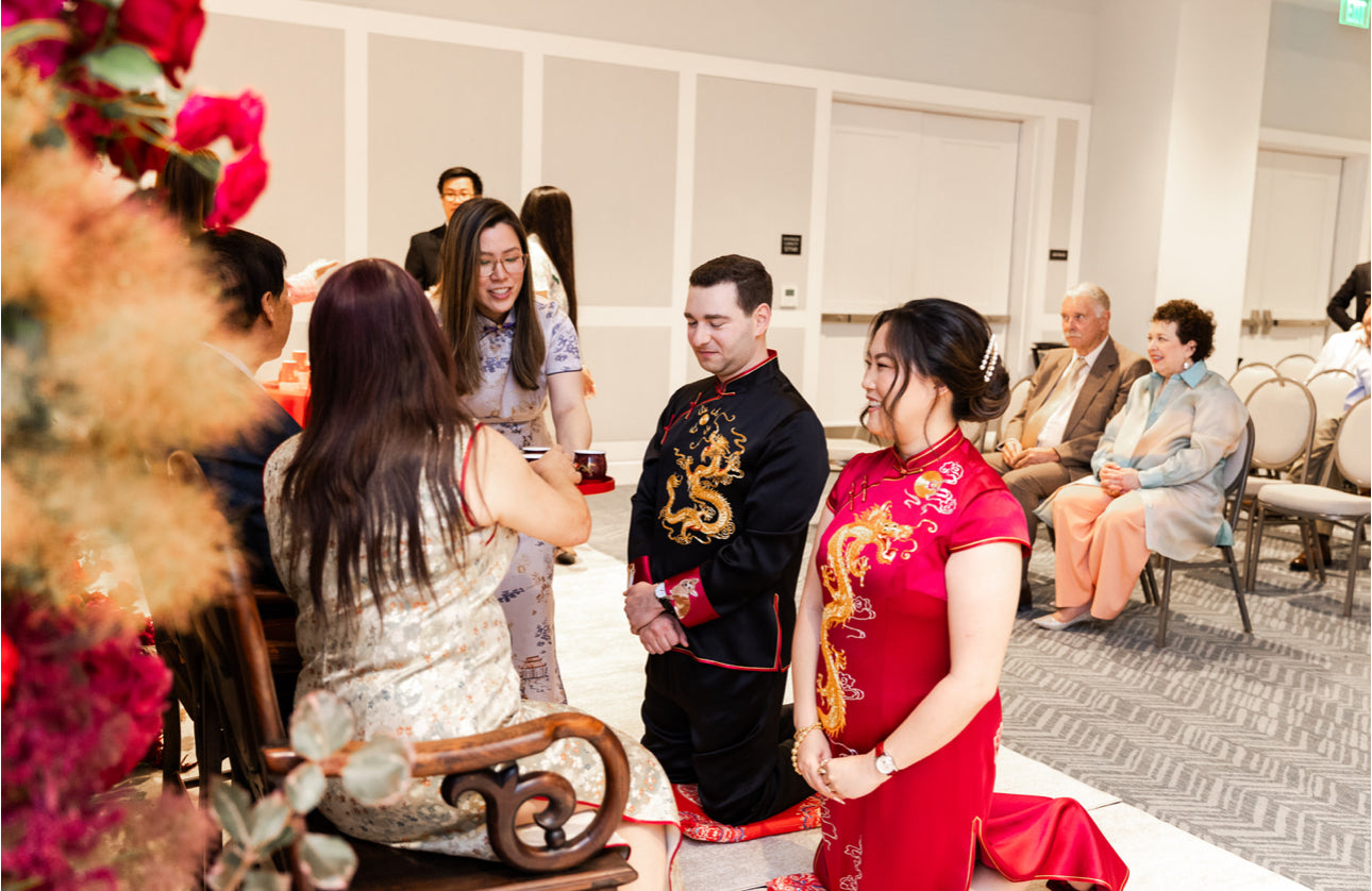 Side view of groom in hand-embroidered black Tang suit set and bride in red silk Qipao handcrafted by JINZA Oriental Couture.