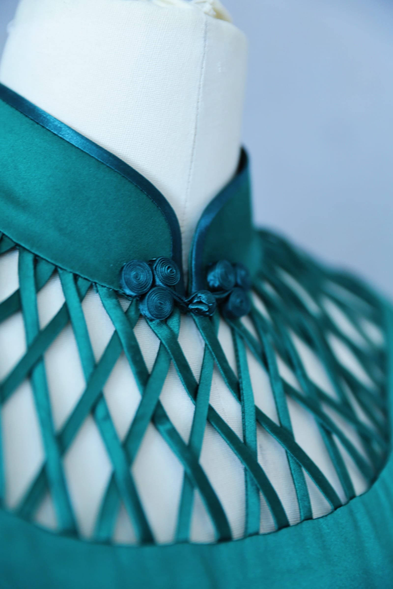 Close up of geometric lattice cutout neckline detail on emerald silk charmeuse Qipao — architectural modern Cheongsam detail by JINZA Oriental Couture, Los Angeles