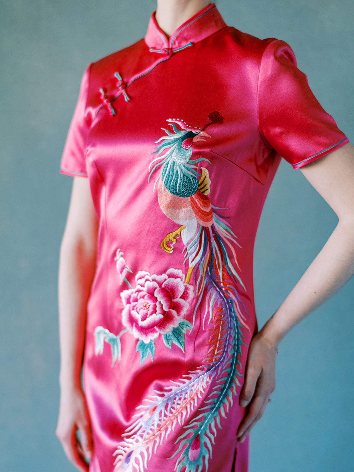 Close-up of hand-embroidered peony flower on fuchsia silk Qipao