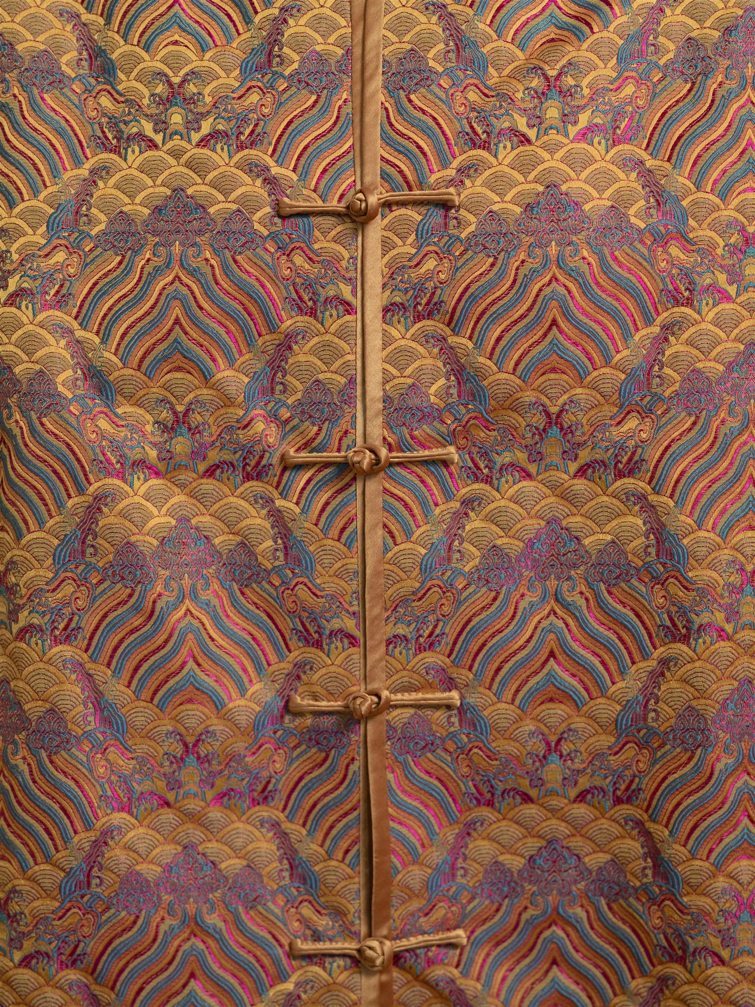 Close-up of sea wave embroidery on gold silk Tang suit.
