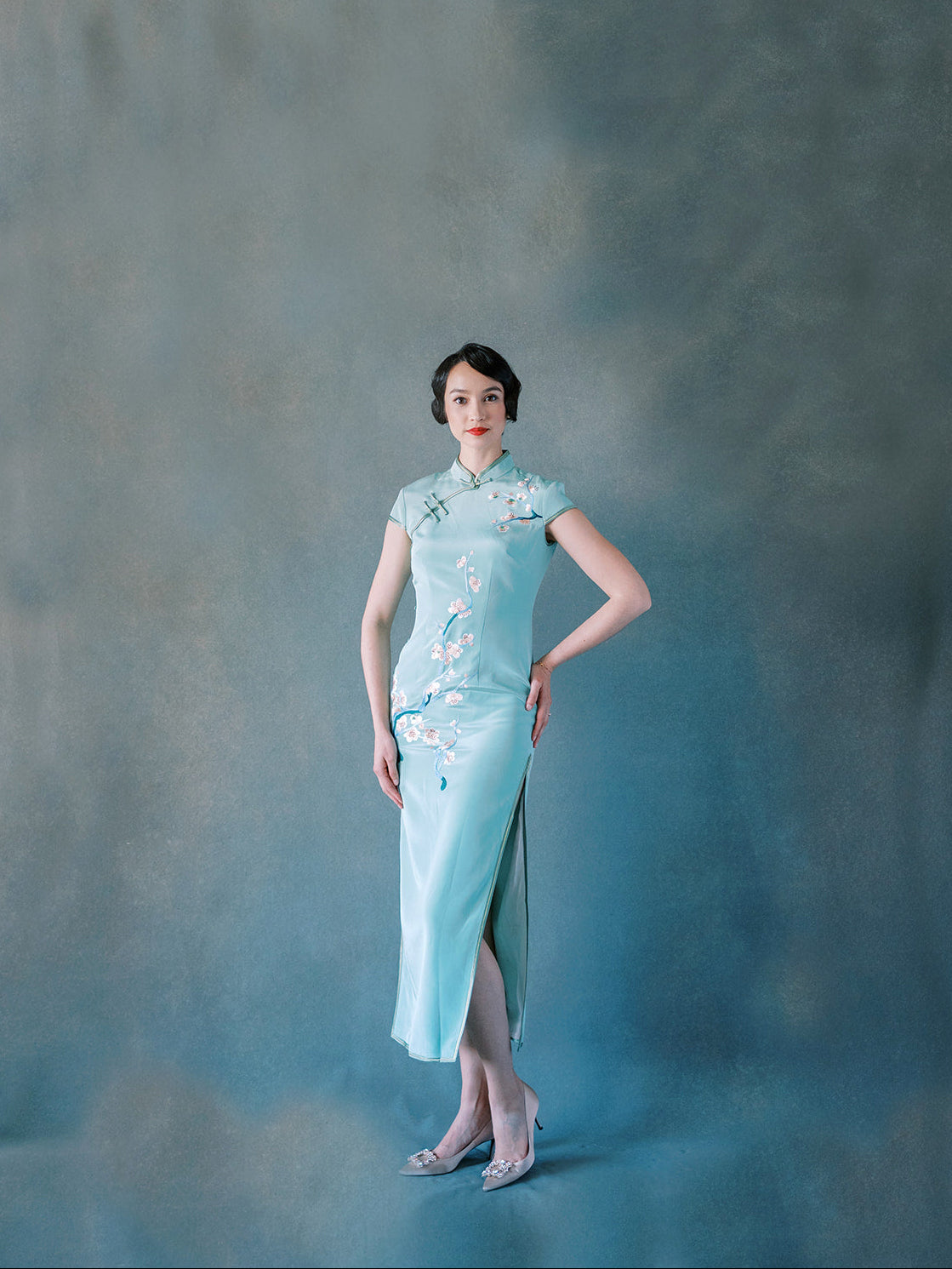 Front view of green silk Qipao with hand-embroidered cherry blossoms.
