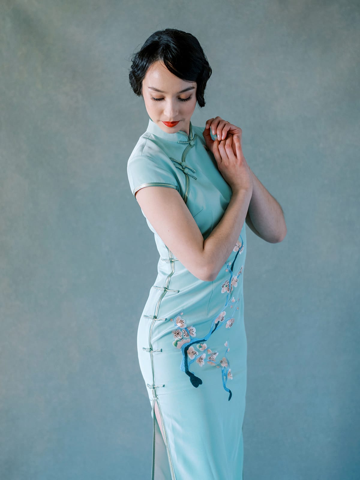 Side view of green silk Cheongsam dress with cherry blossom embroidery.
