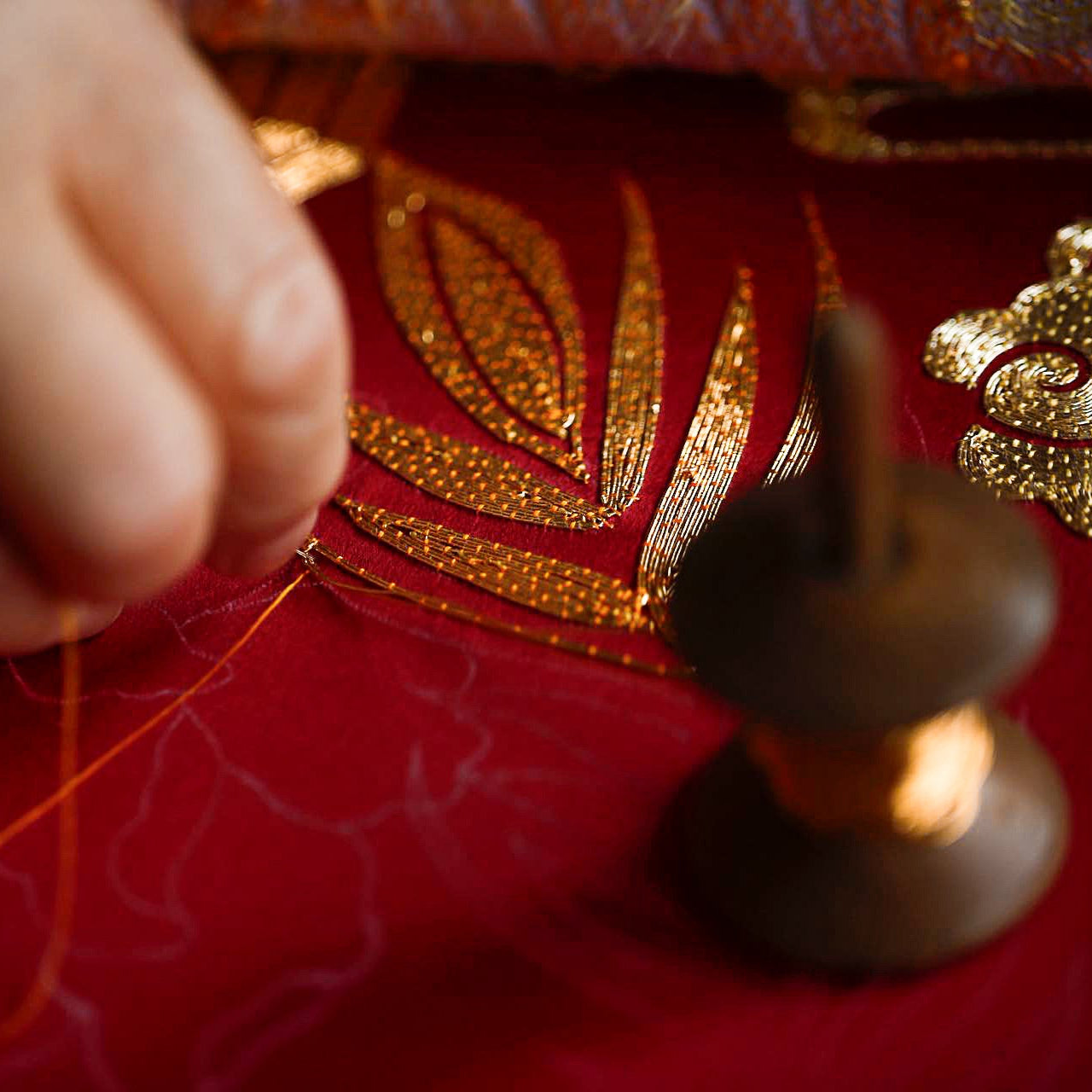 Hand embroidery on red silk Chinese wedding dress, artisan stitching traditional Qipao detail