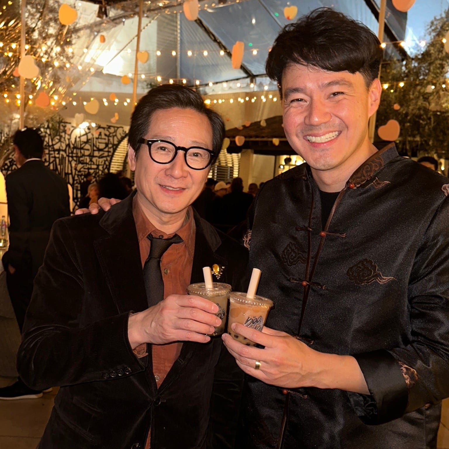 Ke Huy Quan and Philip Wang at the Love Hurts premiere wearing a dark brown modern Tang suit with traditional cloud embroidery by JINZA