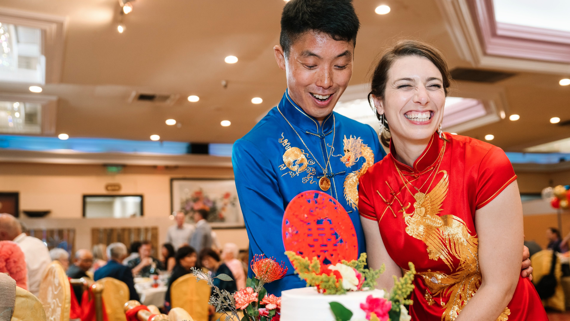 Kevin and Leslie wearing a red Qipao and blue Tang suit at their Chinese tea ceremony, honoring tradition with modern elegance