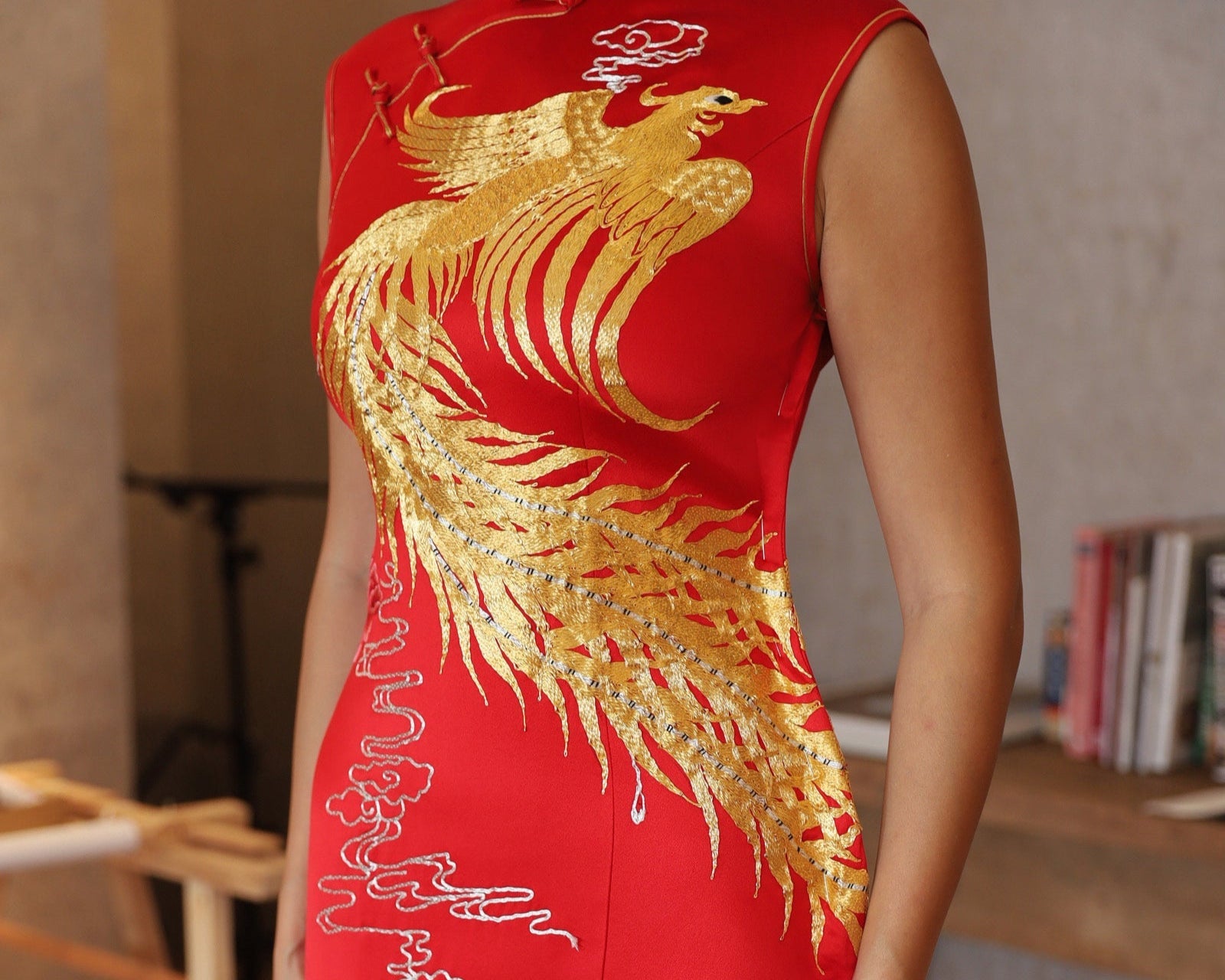 Close-up detail of the gold phoenix embroidery on a modern mermaid-style red Cheongsam wedding dress with a train, designed for weddings.