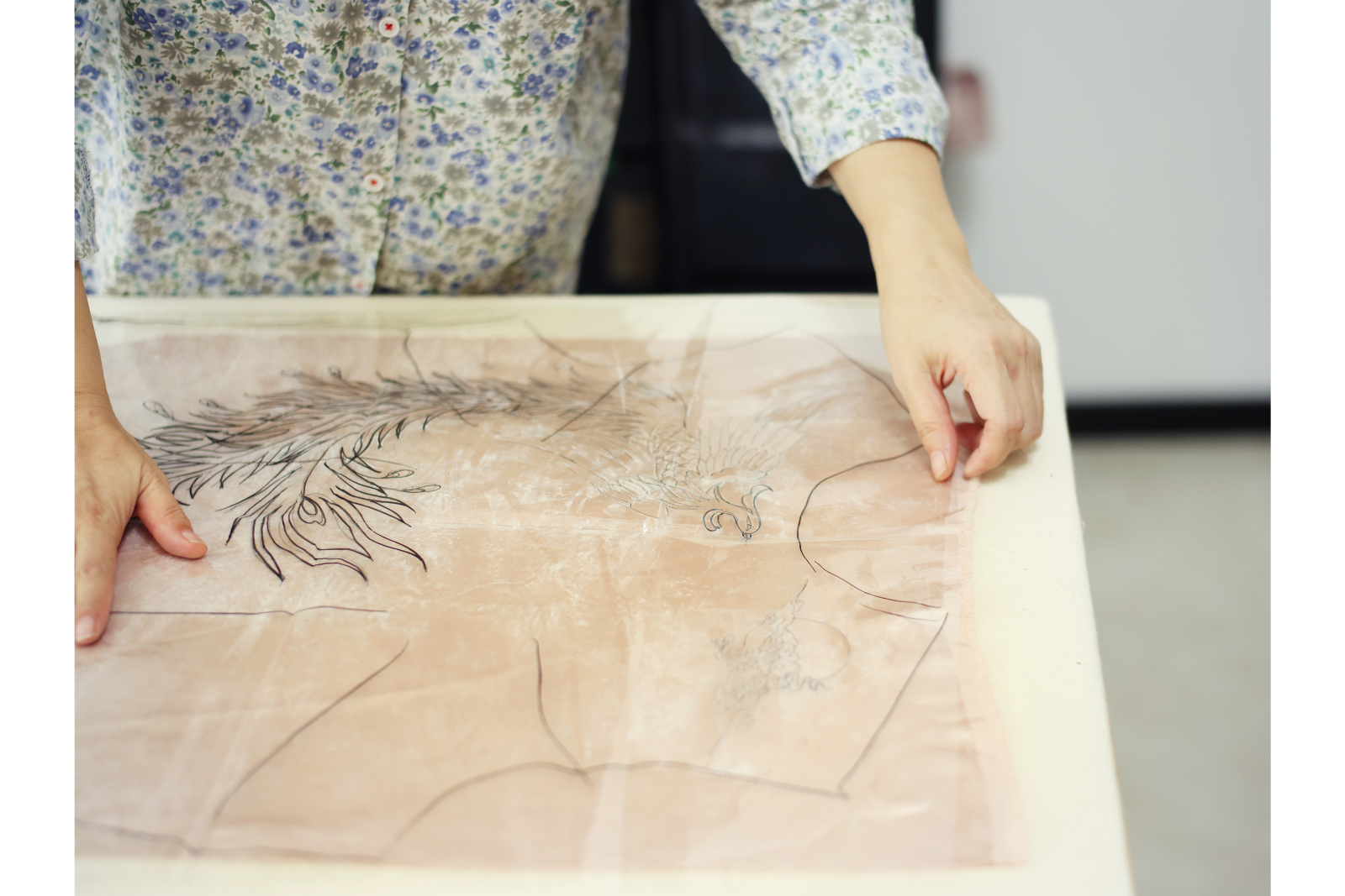 Artisan planning embroidery placement on red silk for a Chinese wedding Qipao
