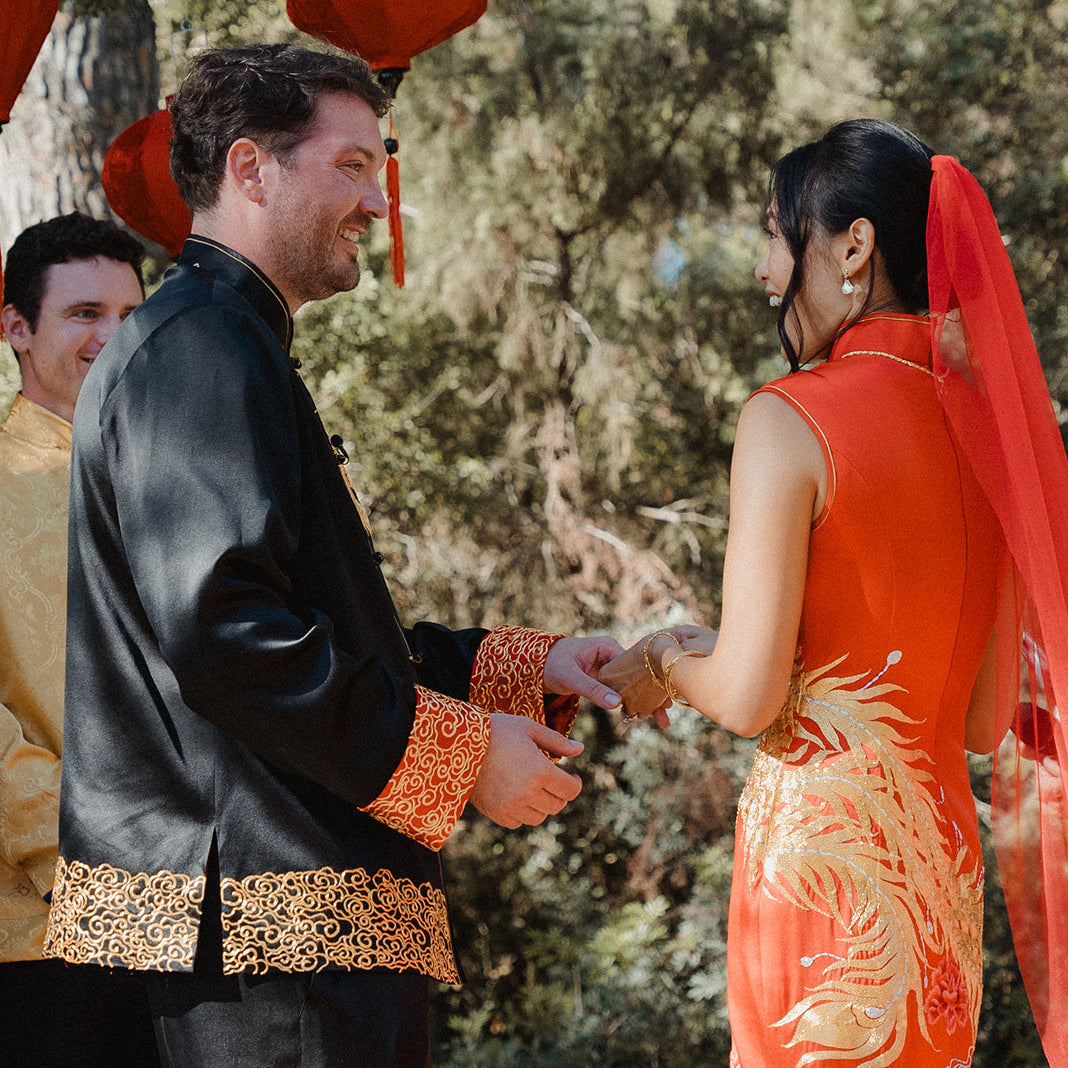 Shirley in red silk mermaid Qipao with phoenix and peonies, and Ted in black Tang suit with dragon and clouds at their Ibiza destination wedding