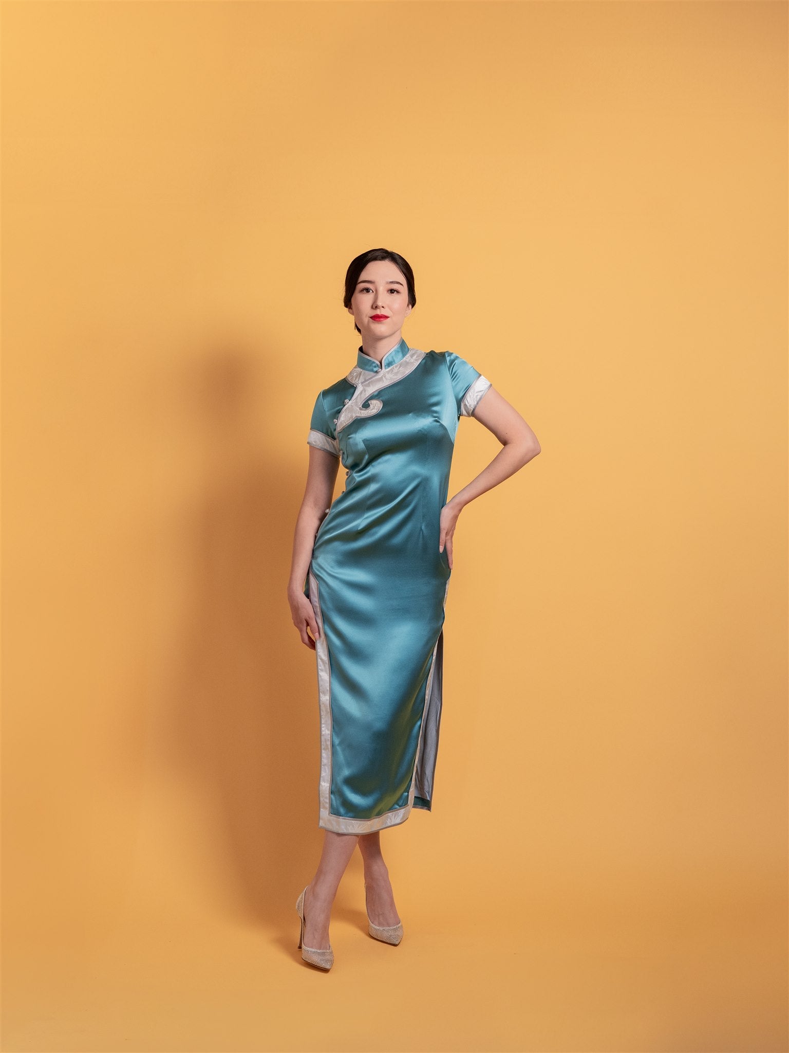 Teal silk cheongsam with silver piping and cap sleeves, front view