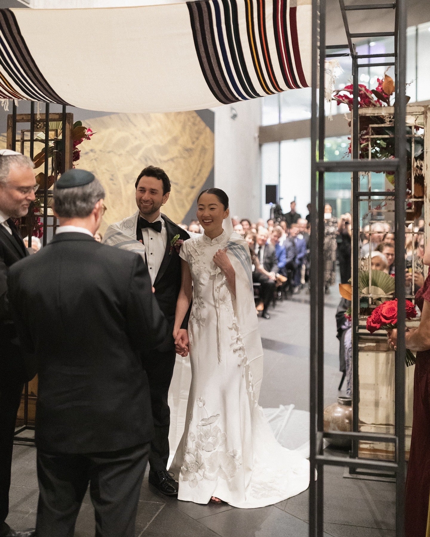 Real bride Connie wearing a white silk crepe modern wedding Cheongsam with hand-embroidered lotus and pomegranate motifs at her Jewish wedding, designed by JINZA Oriental Couture.