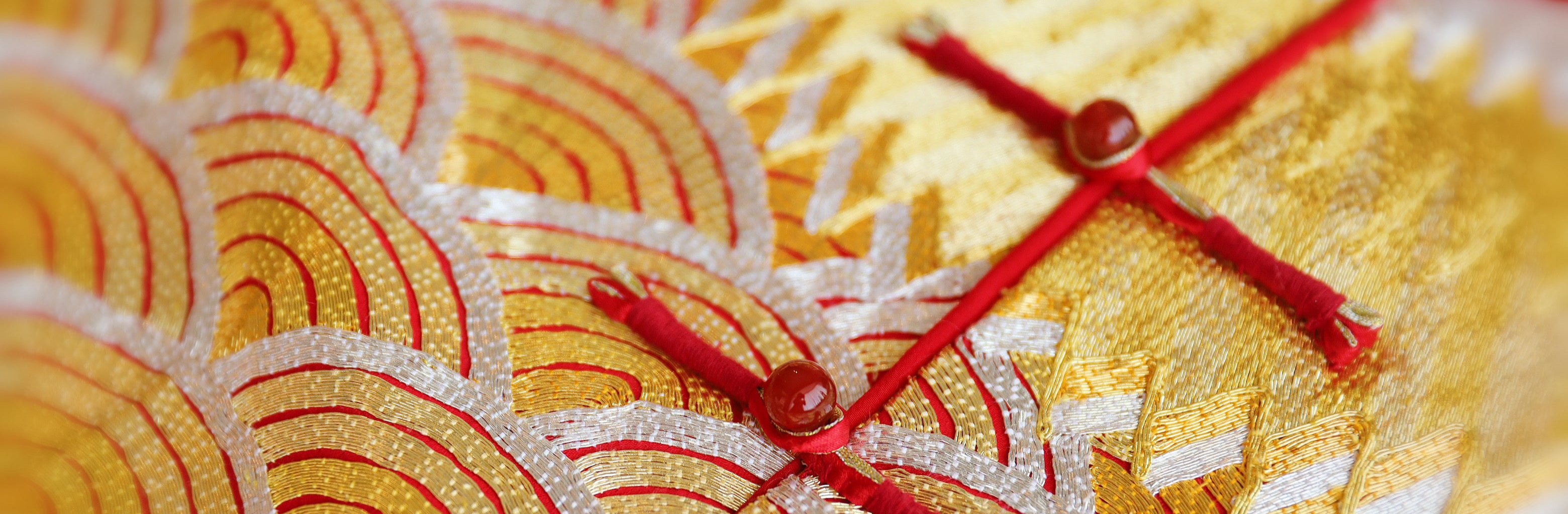 Close-up of the Qun Kwa gold and silver embroidery with red Pankou knot buttons. 