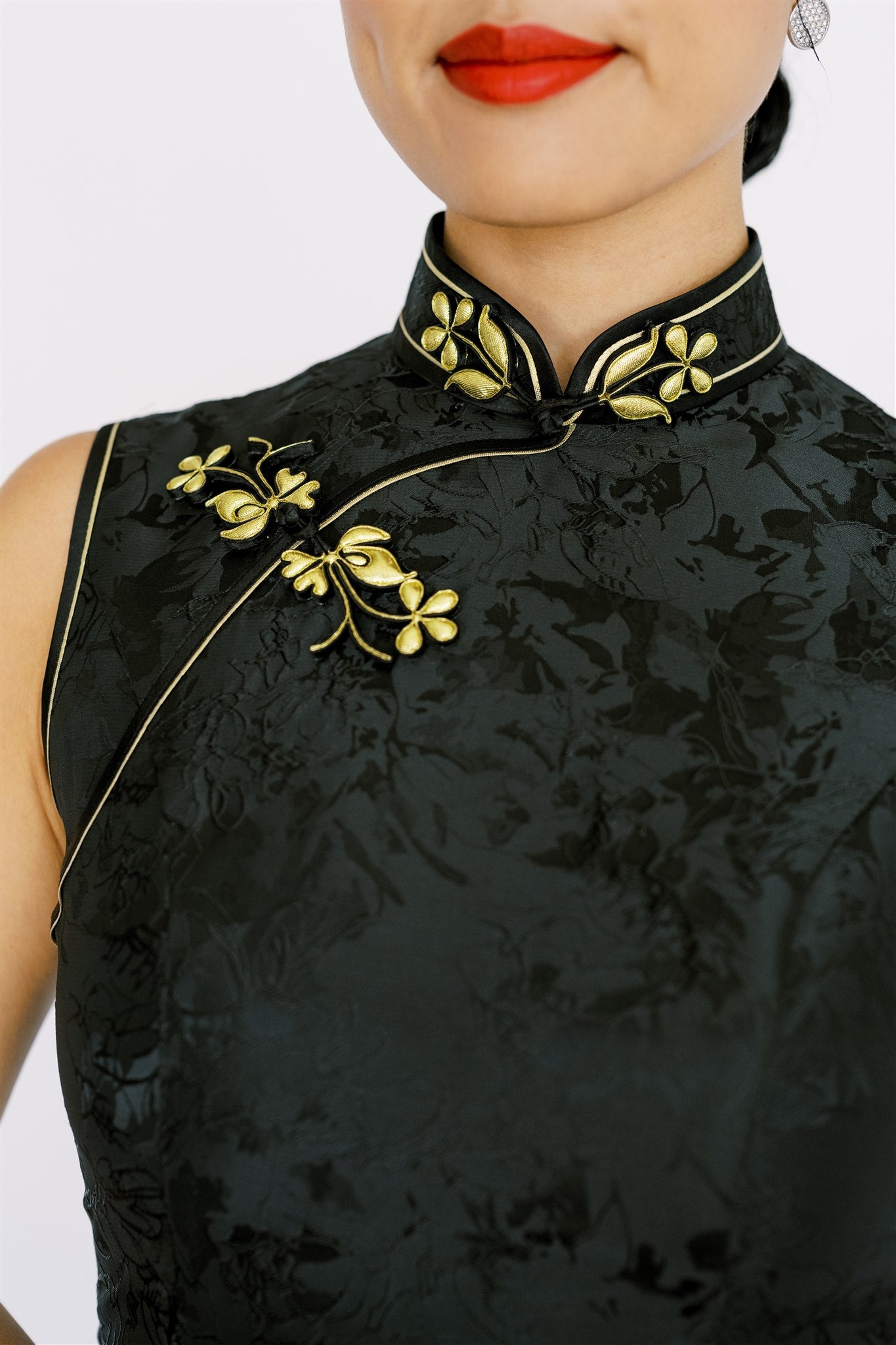 Gold floral pankou knot details on a modern black Qipao