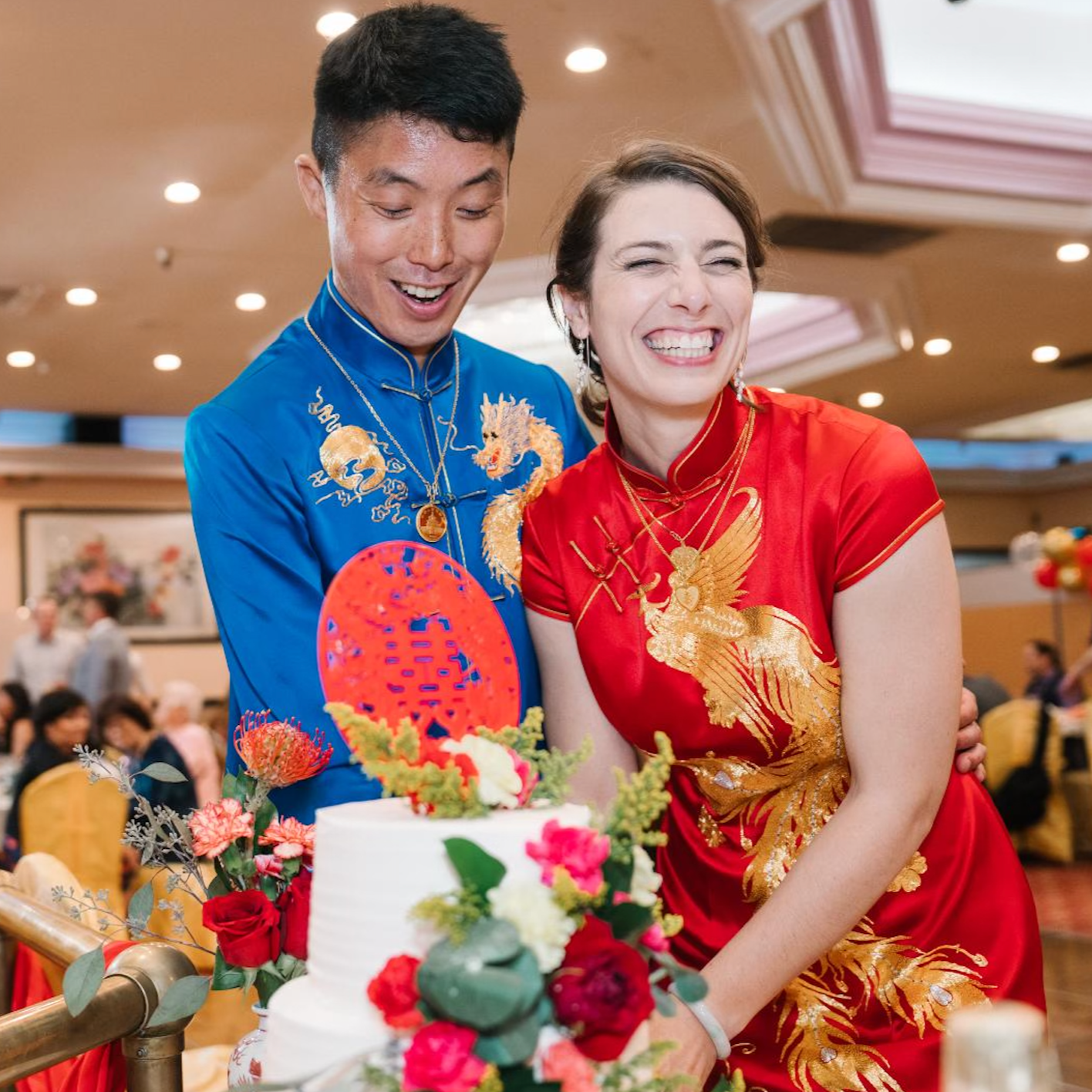 A couple wearing matching blue silk tang suit and red Qipao at their Chinese banquet