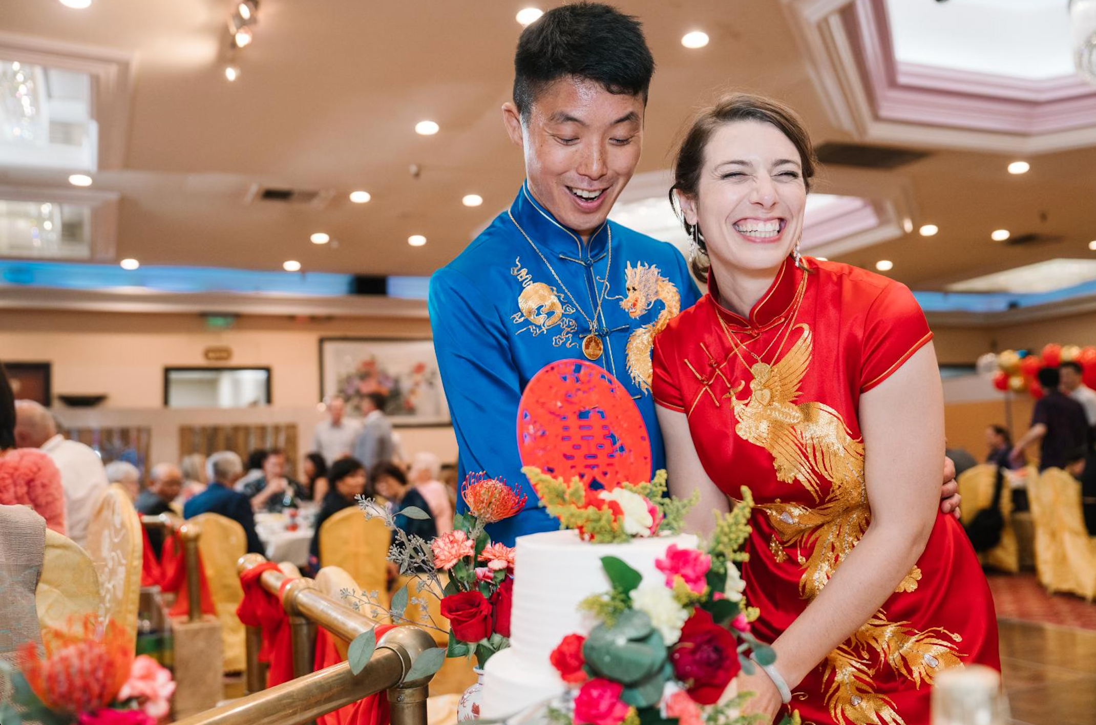 A couple wearing matching blue silk tang suit and red Qipao at their Chinese banquet