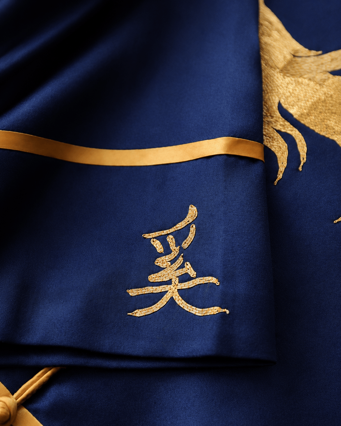 Close up of gold Chinese family name character hand embroidered on bespoke navy silk Tang suit, personalisation detail at JINZA Los Angeles
