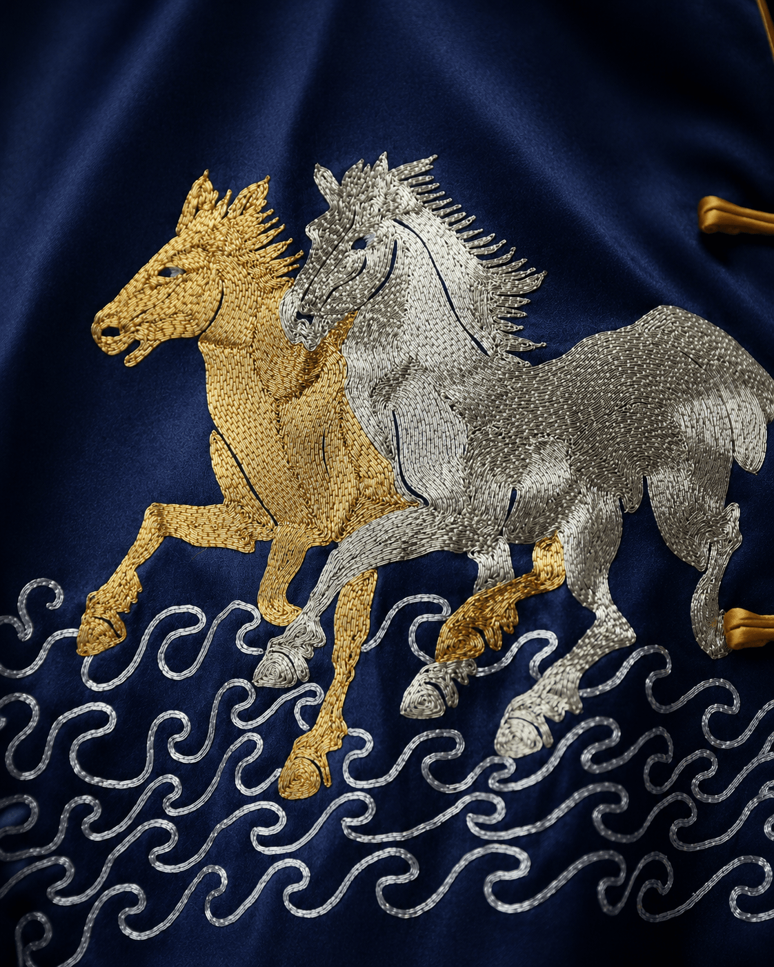 Close up of gold and silver horse hand embroidery with sea wave pattern on bespoke navy silk Tang suit, custom made at JINZA Los Angeles
