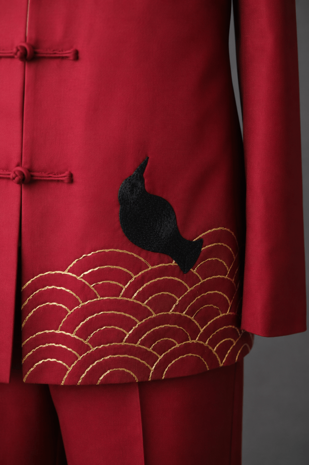 Close up of black bird embroidery with gold sea wave pattern on bespoke red silk Tang suit, custom made at JINZA Los Angeles