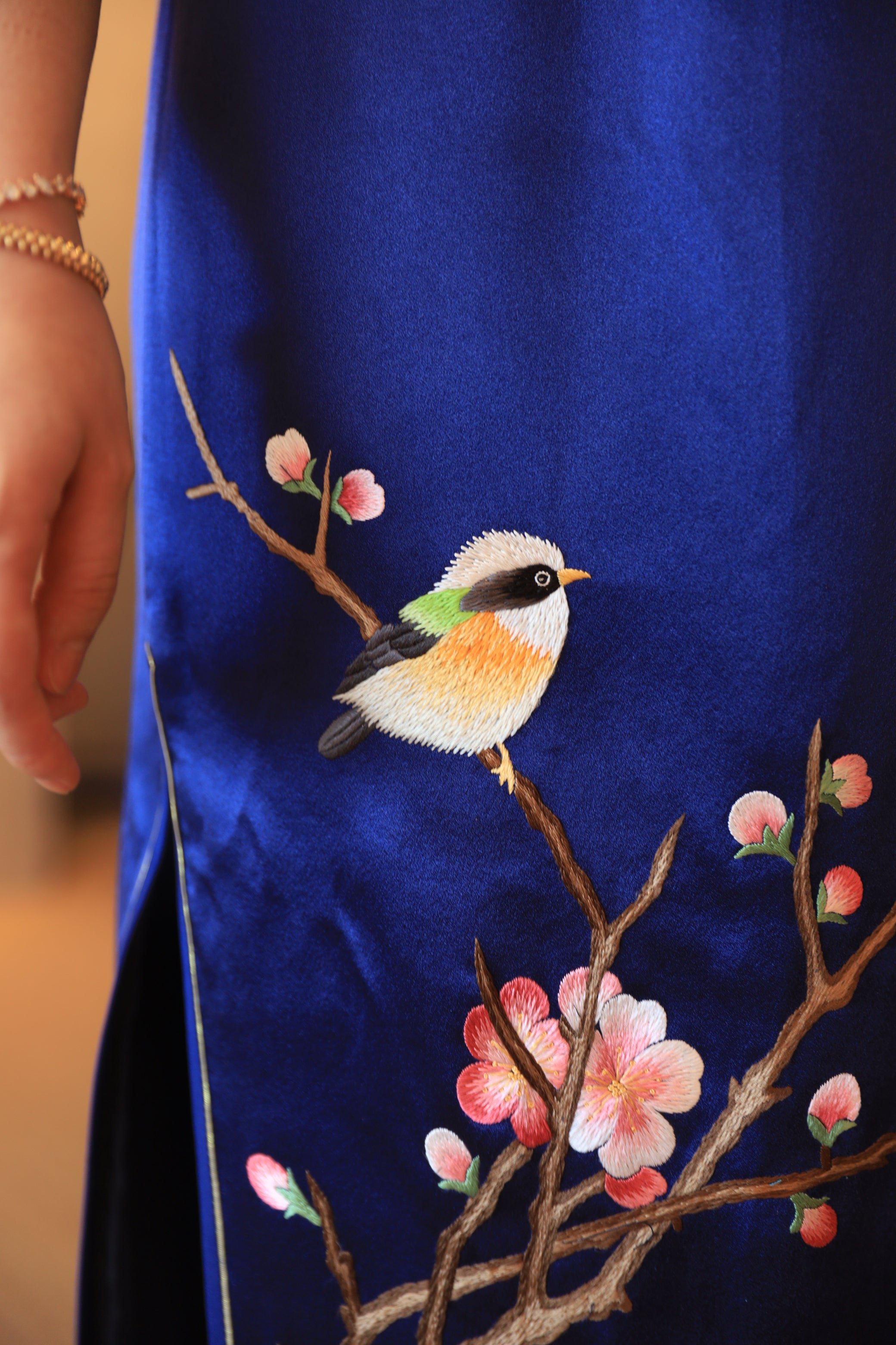 Bird and cherry blossom details on a blue silk Qipao