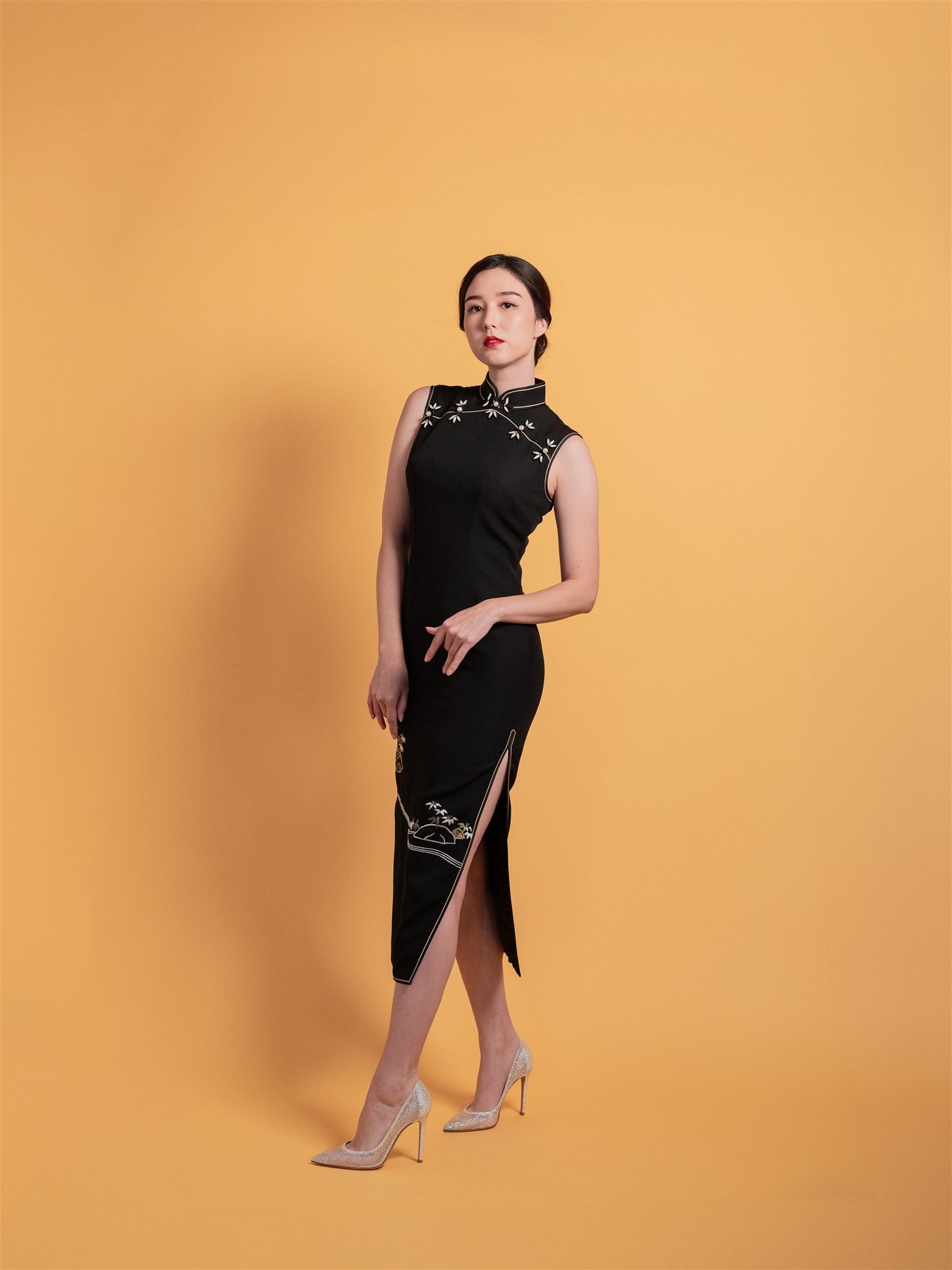 Side view of black silk Qipao/Cheongsam with intricate hand embroidery of bamboo, river, and rocks, designed with a sleeveless cut and mid-calf length.