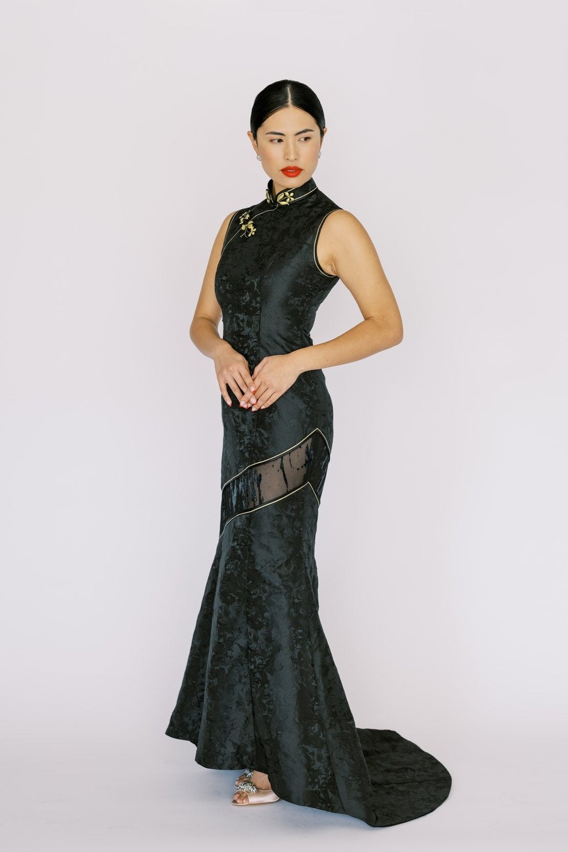 A woman wearing a mermaid black Cheongsam with a modern train and lace cut-out