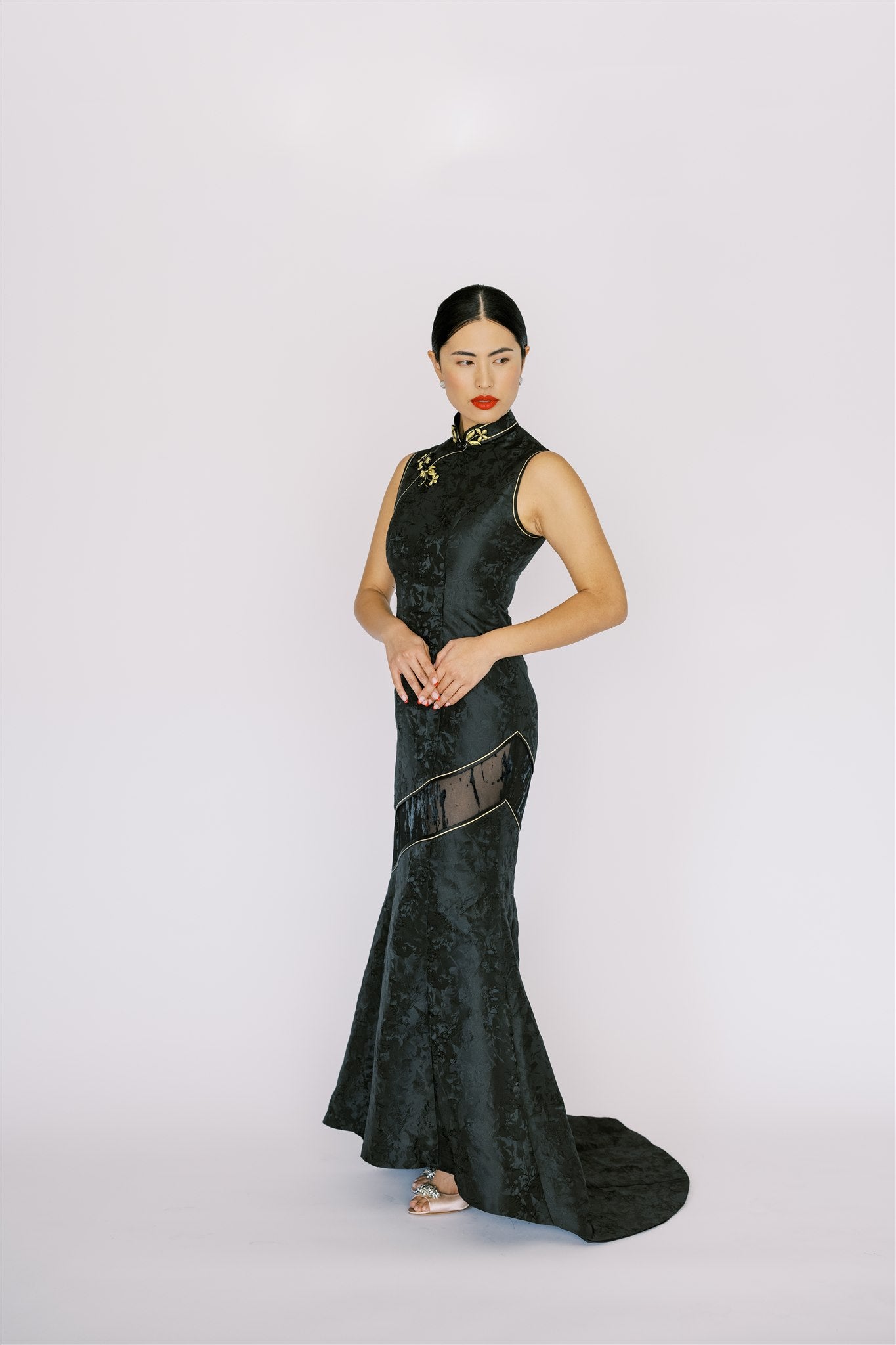 A woman wearing a mermaid black Cheongsam with a modern train and lace cut-out