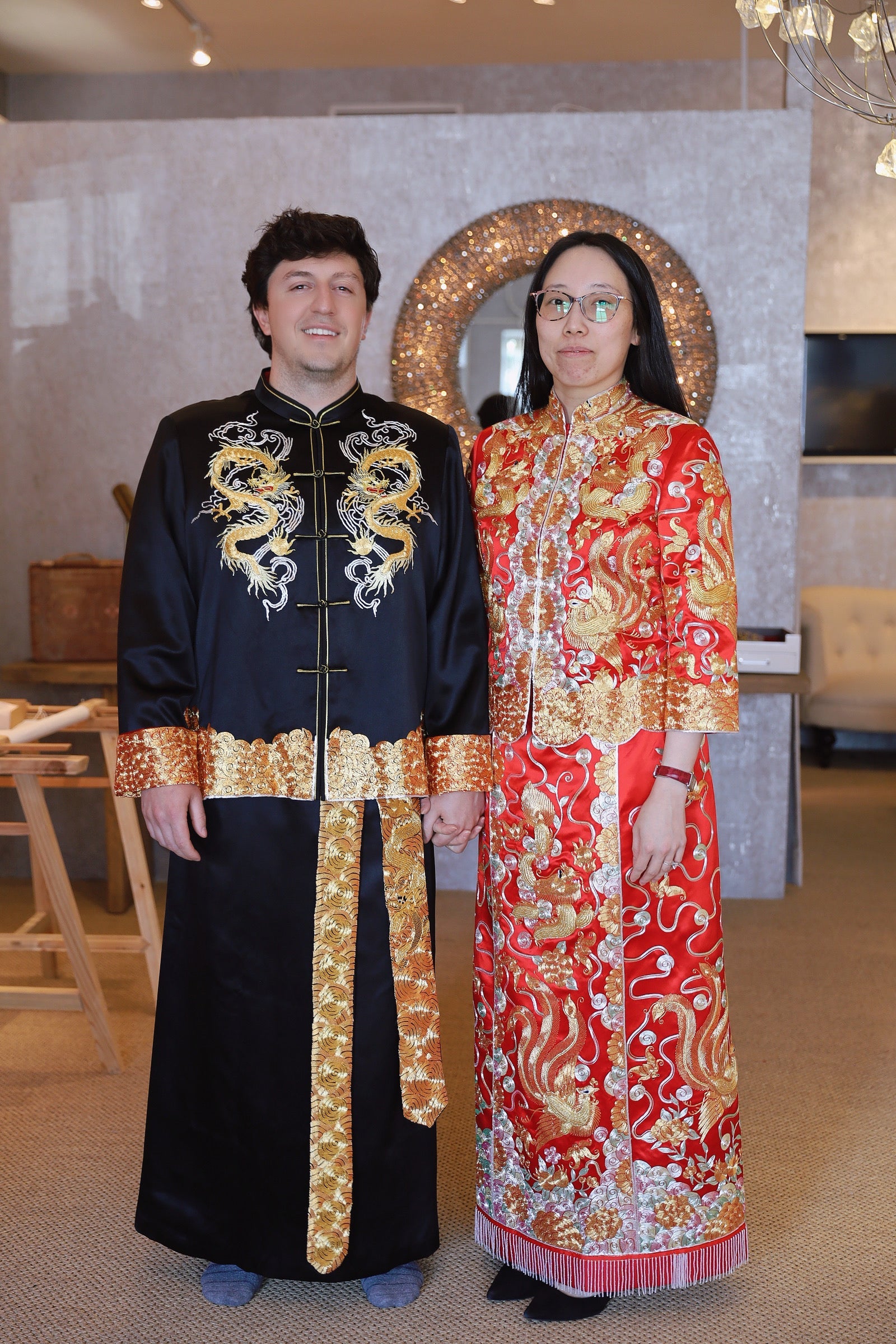 A groom wearing a black silk tang suit with two dragons and a black skirt