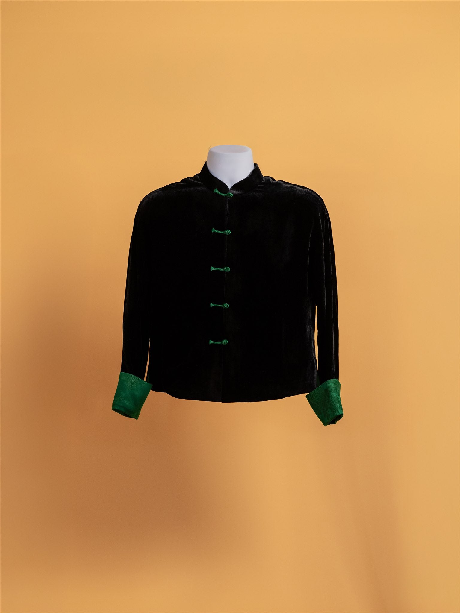 Front view of a black silk velvet tang suit with green silk brocade lining and calf, also featuring green frog knot buttons, perfect for daily wear. 