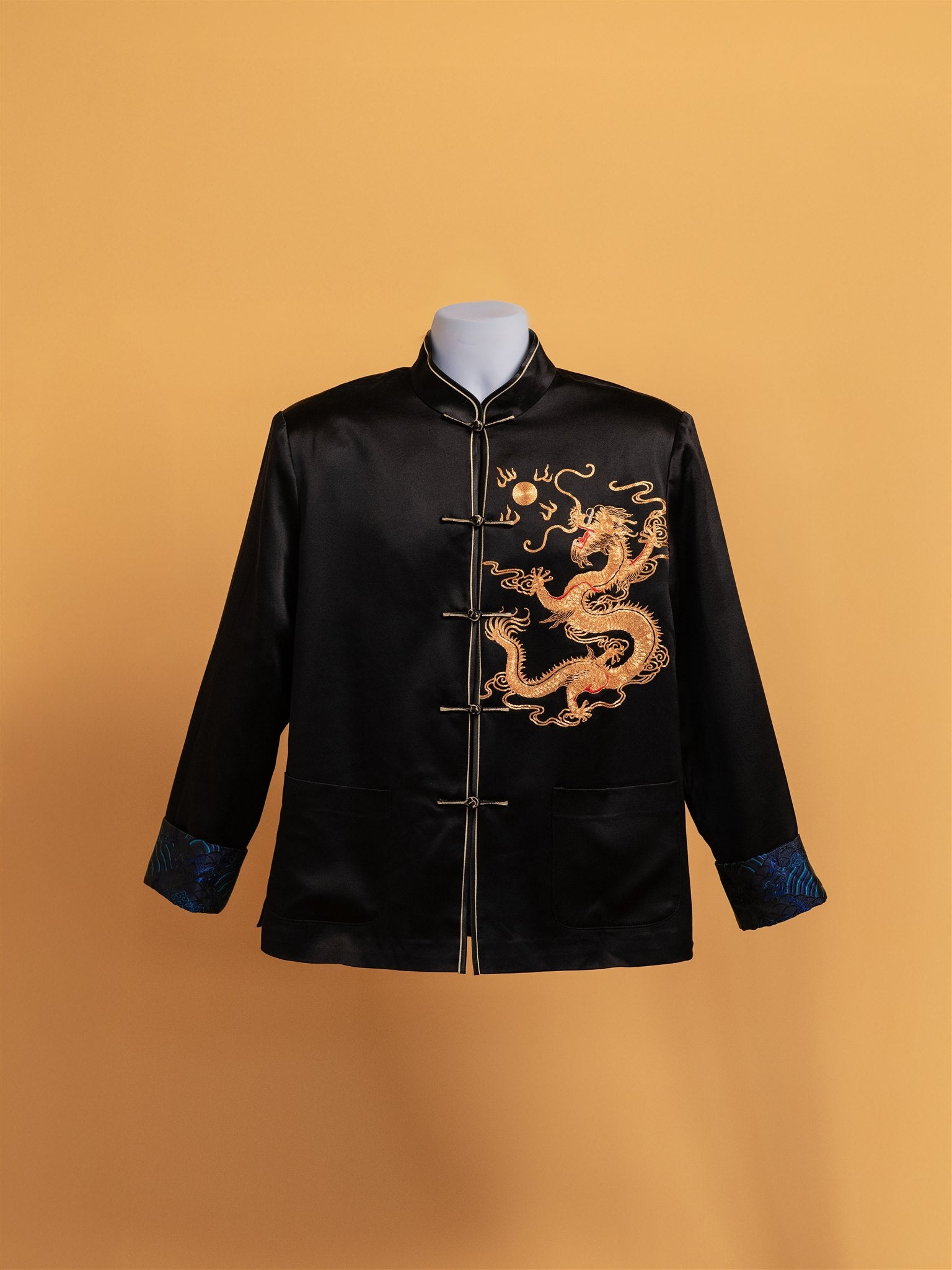 Front view of black Tang suit wedding jacket with gold dragon embroidery and blue brocade lining.