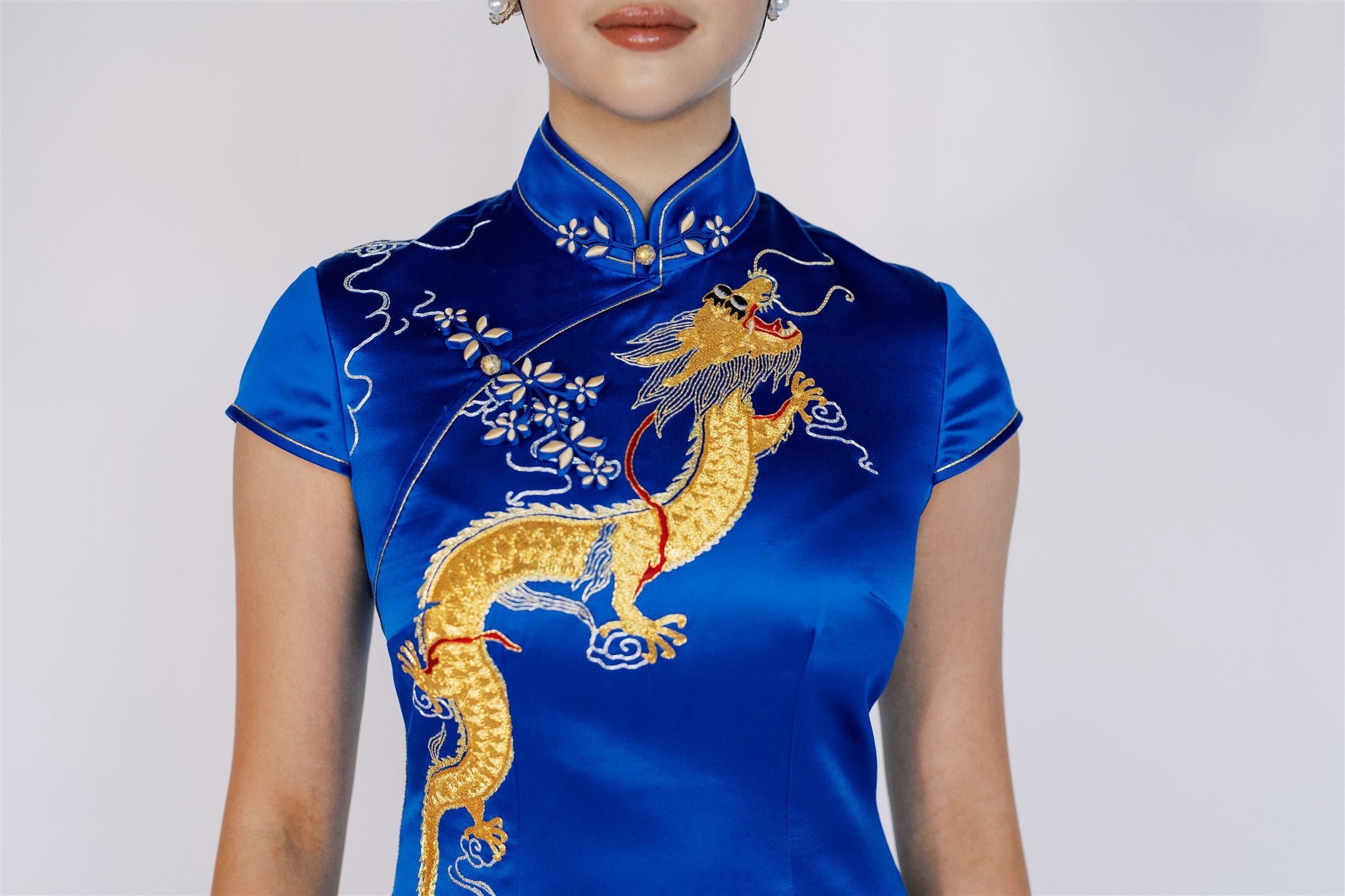 A girl wearing a royal blue qipao with gold dragon hand embroidery