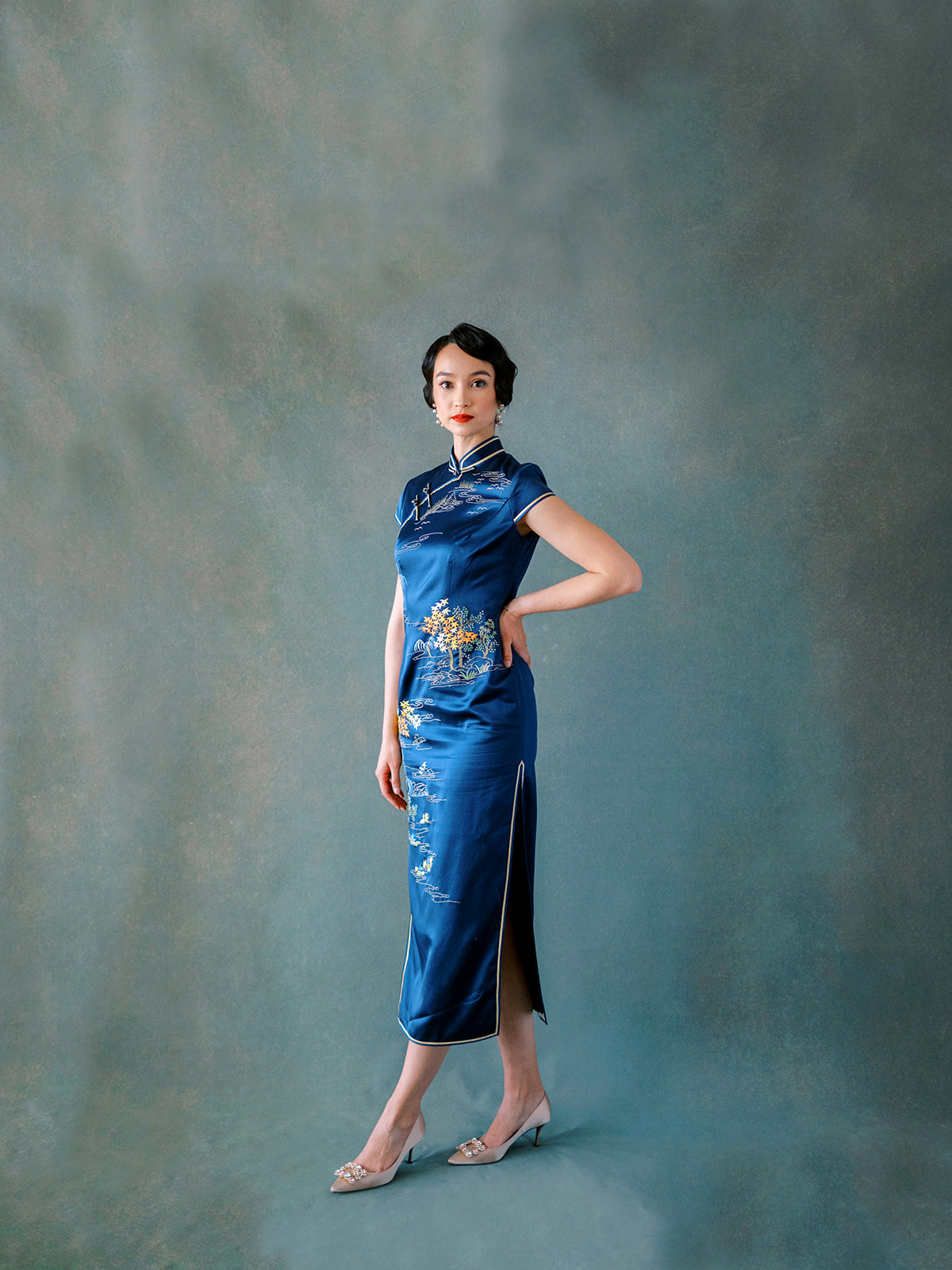 Front view of blue silk Qipao dress with hand embroidery of mountain, lotus pond, and birds.