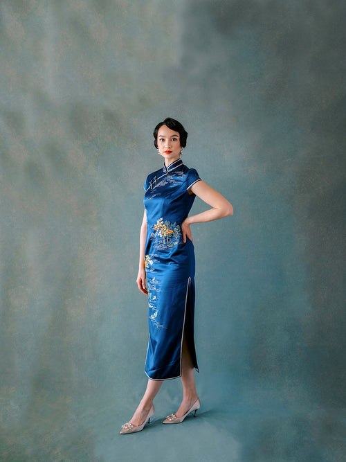 Front view of blue silk Qipao dress with hand embroidery of mountain, lotus pond, and birds.
