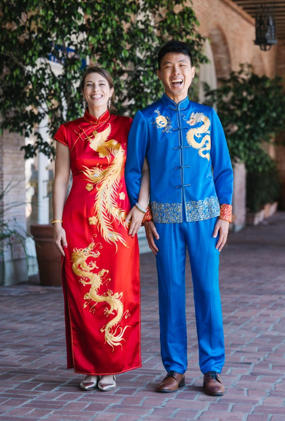 Couple wearing blue silk Tang suit with gold dragon embroidery and red wedding Qipao with phoenix and dragon embroidery