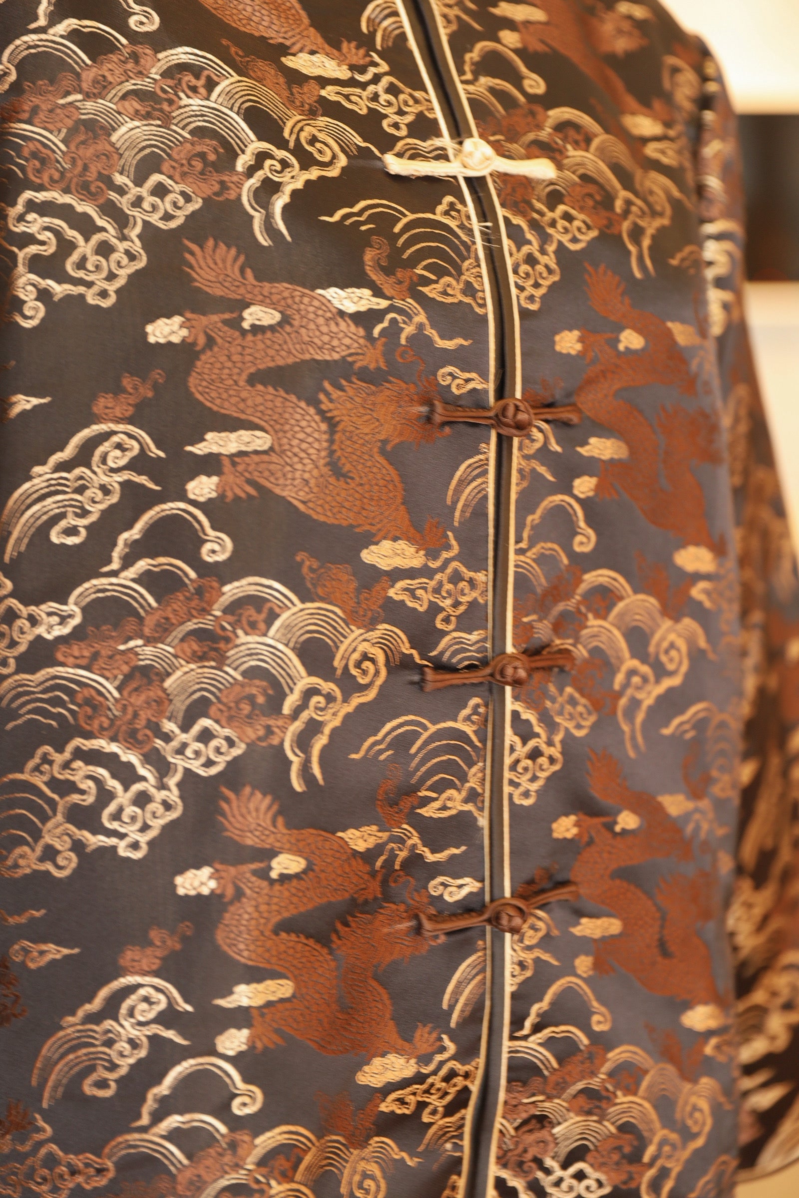 Close-up detail of the dragon, cloud and frog knot buttons on the tang suit. 