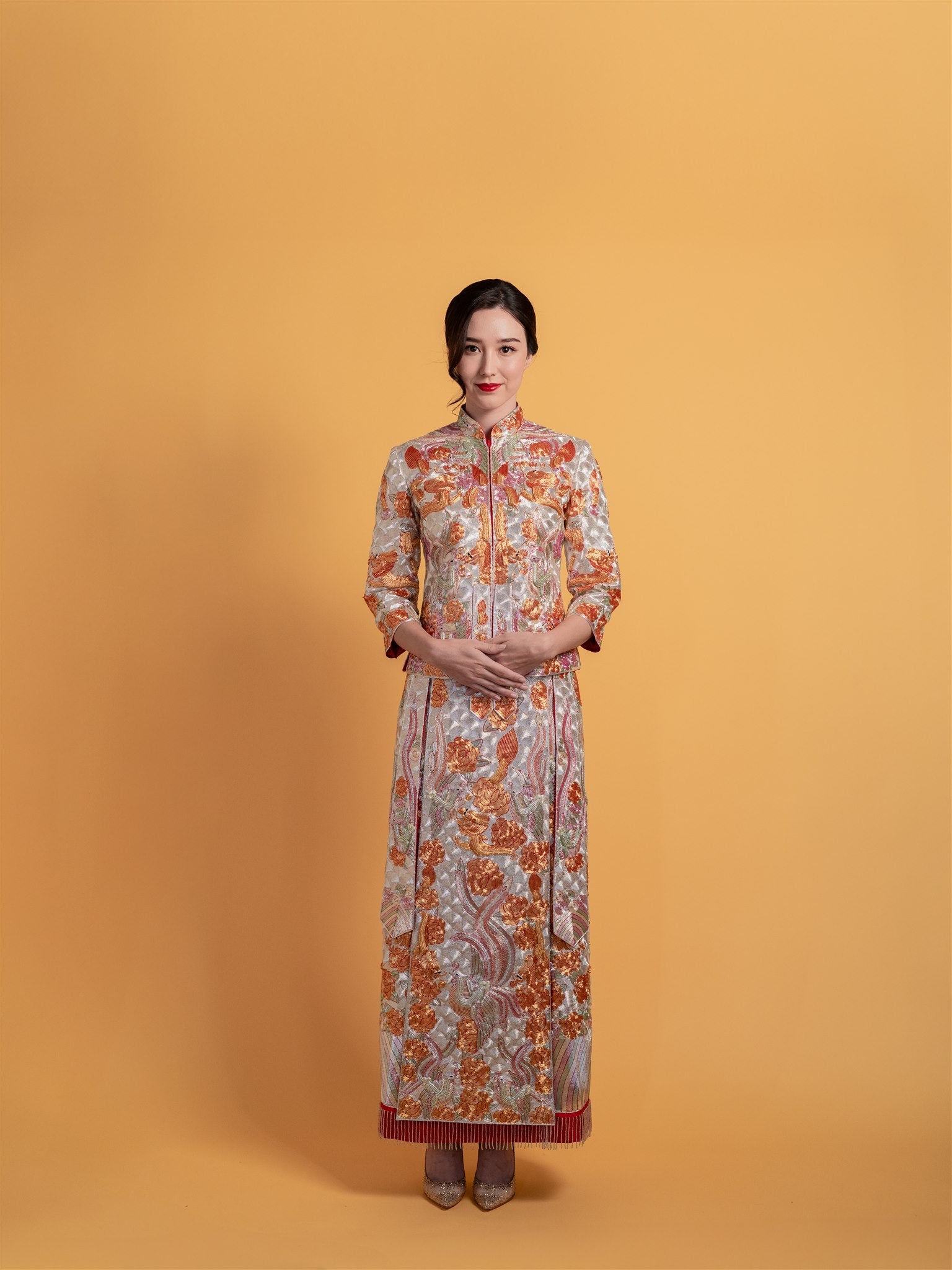 Front view of a bride wearing the silver Chinese wedding dress Qun Kwa: King Kwa, featuring silver and gold hand-embroidered dragon, phoenix, and bats patterns.