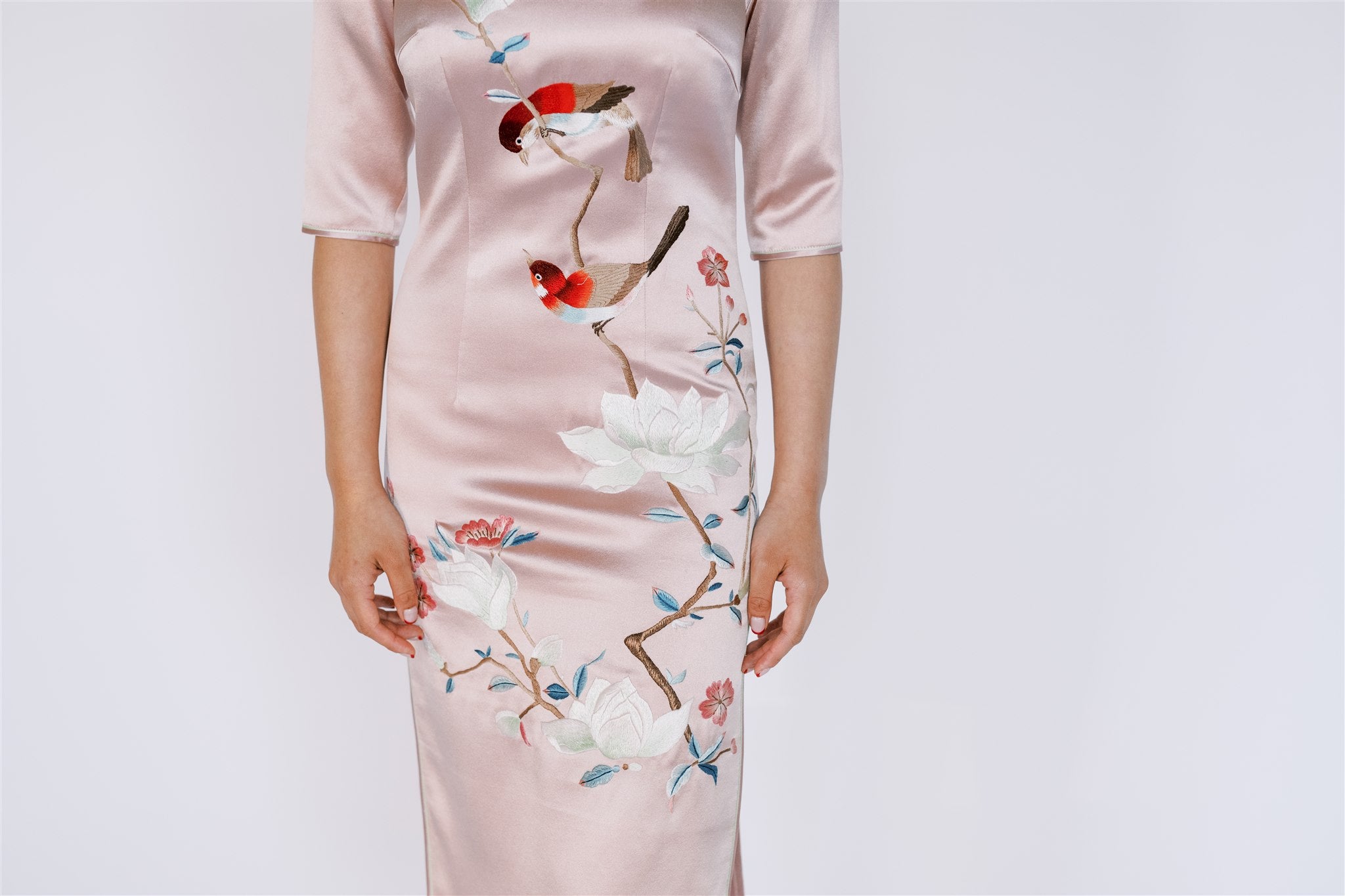 Detailed view of intricate handcrafted mangnolia flowers and birds on Pink Wedding Qipao.