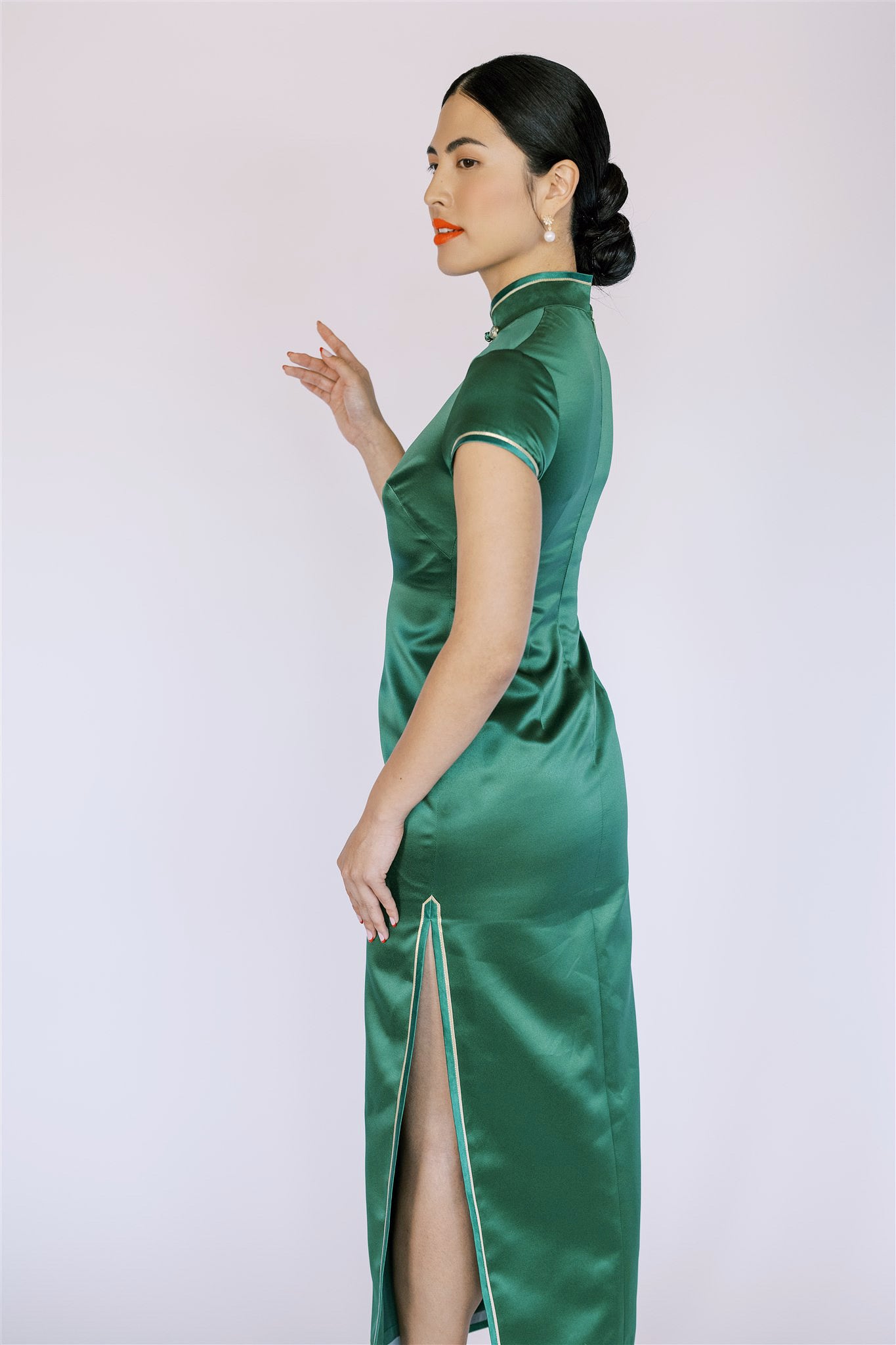 Side view of side slit detail on emerald green Qipao, featuring a refined touch blending tradition and comfort.