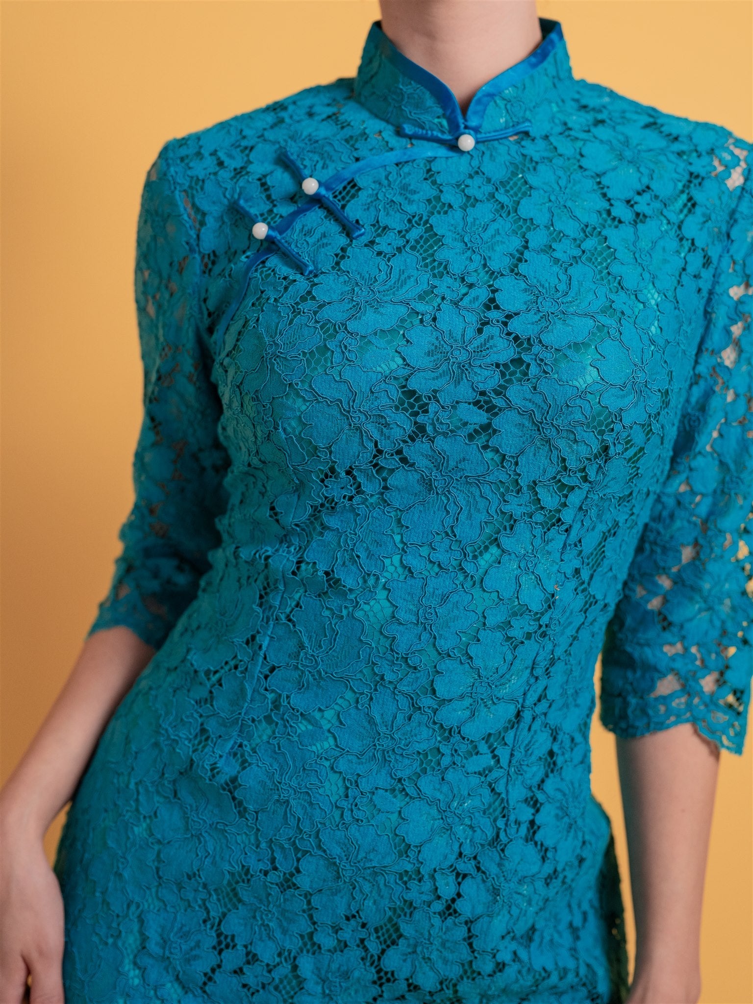 Close-up detail of cotton lace fabric on blue Qipao, it is an intricate lace details for a soft, elegant look.