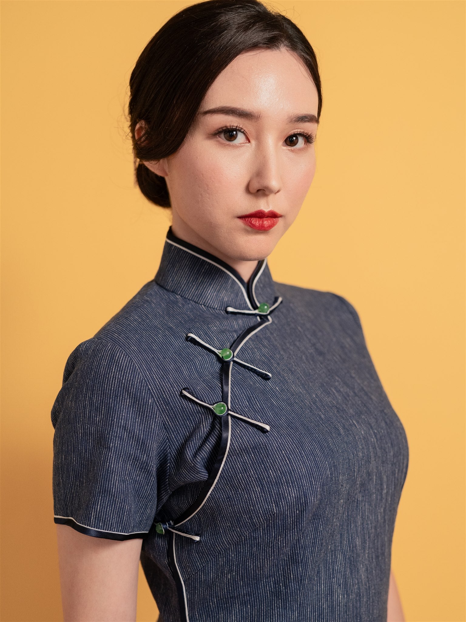 Close-up detail of classic button closure on 1930s Qipao dress, featuring emerald Pankou knot and mandarin collar, with cap sleeves, mid-calf length.