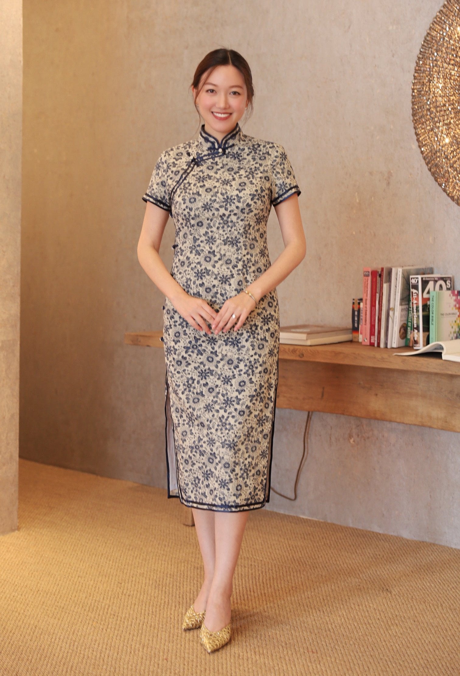 A client wearing JINZA Oriental Couture's Qipao in blue French linen with cap sleeves, with double hand-binding trim.