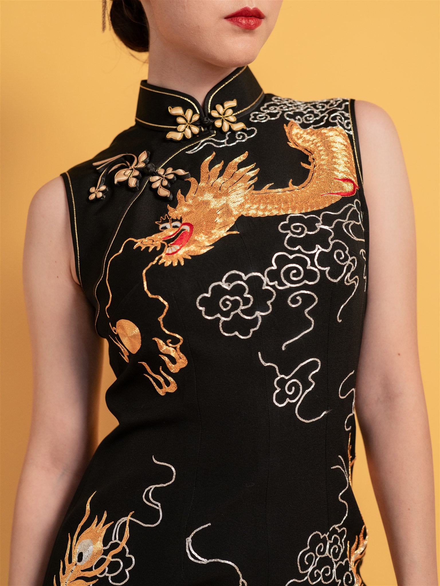 Detailed view of the dragon and cloud motifs on classic black Qipao dress, with an intricate gold embroidery representing power and harmony.
