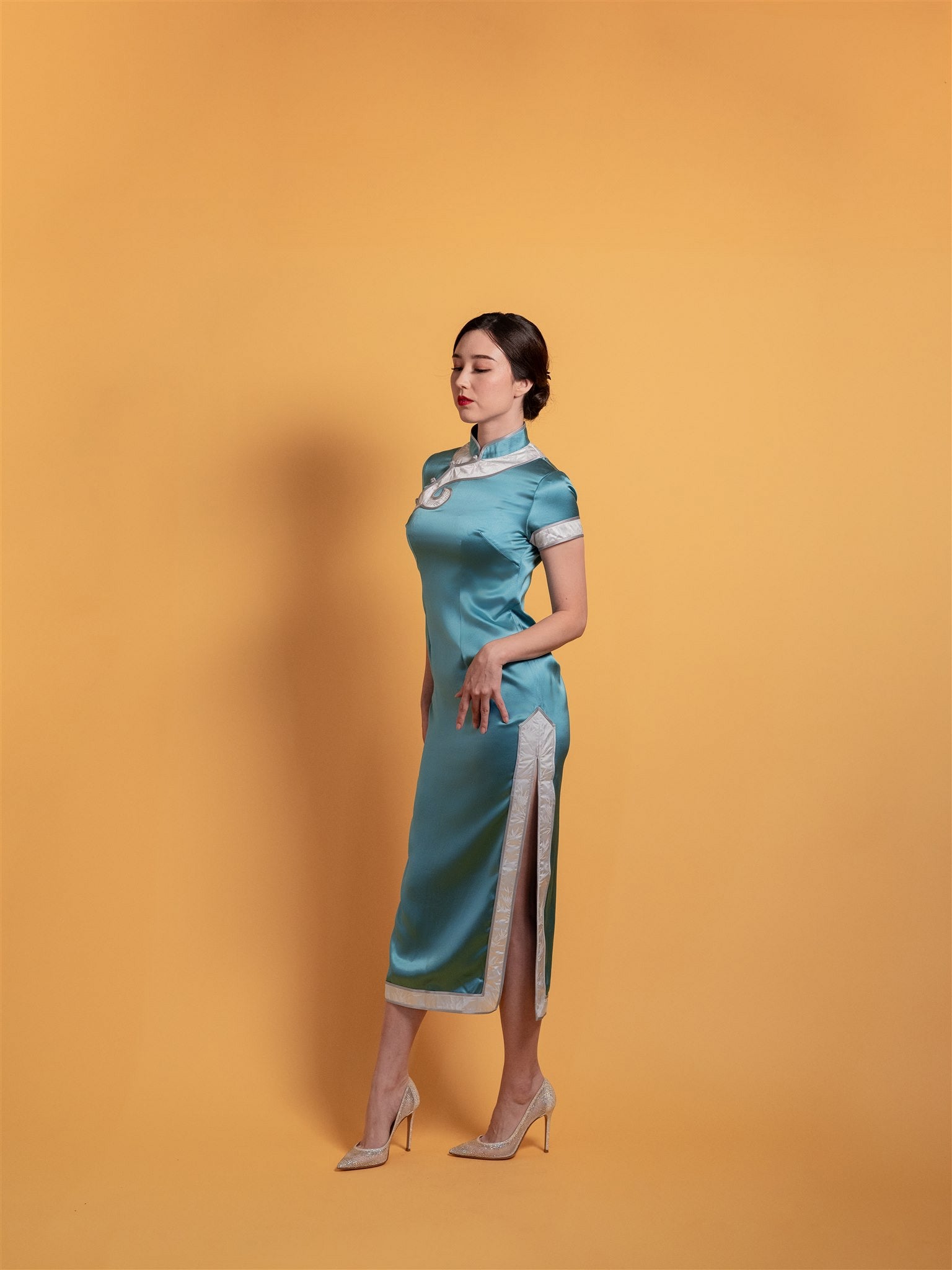 Side view of a peacock silk Qipao featuring grey contrasting trim and collar, and side slit details. 