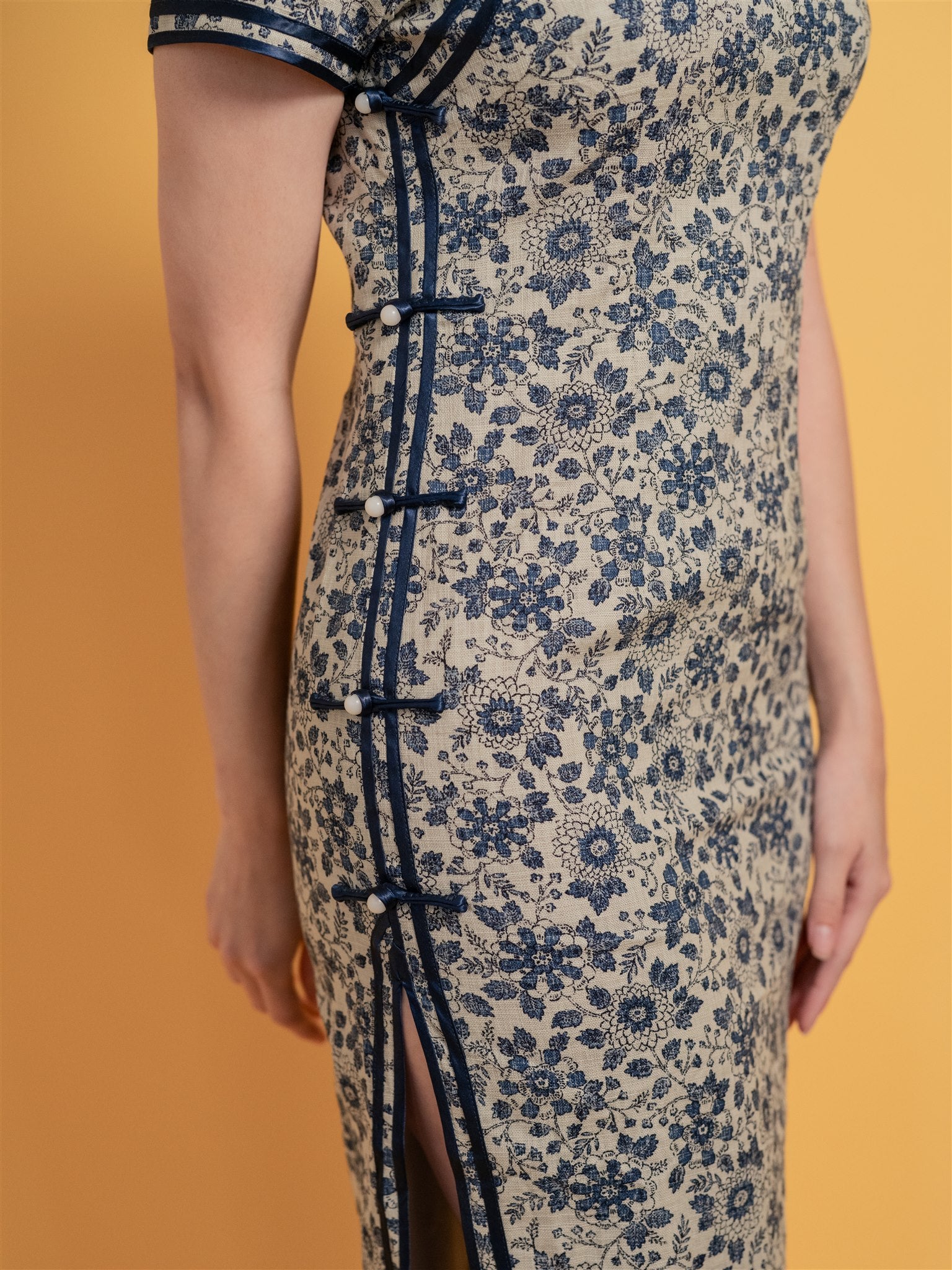 Close-up detail of navy blue piping and Pankou detail on classic Qipao dress, a heritage-inspired touch on a linen qipao dress.