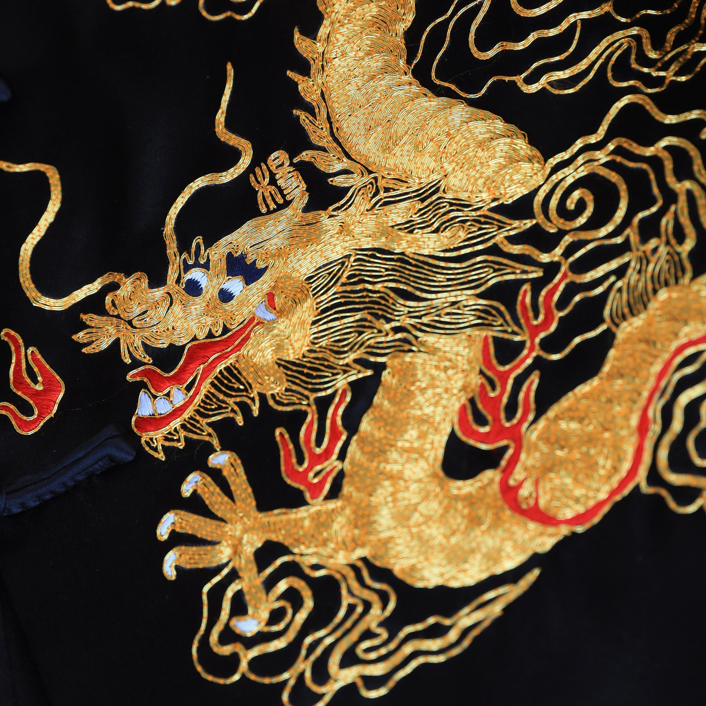 Close-up of gold dragon embroidery on black silk Tang suit.