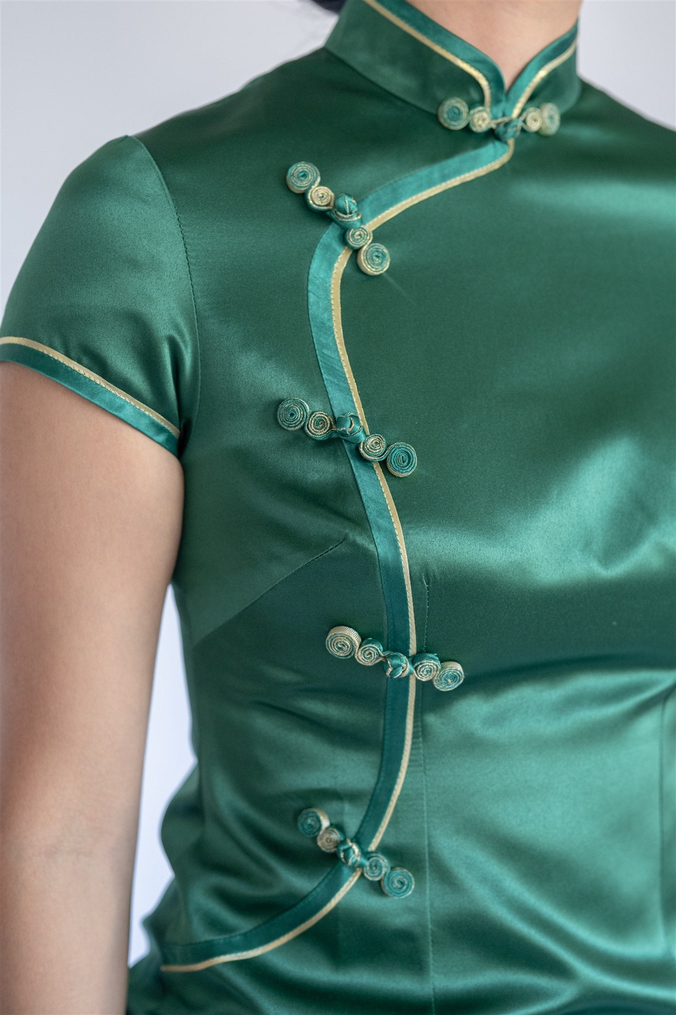 Detail of silk fabric and wavy neckline on emerald green Cheongsam.