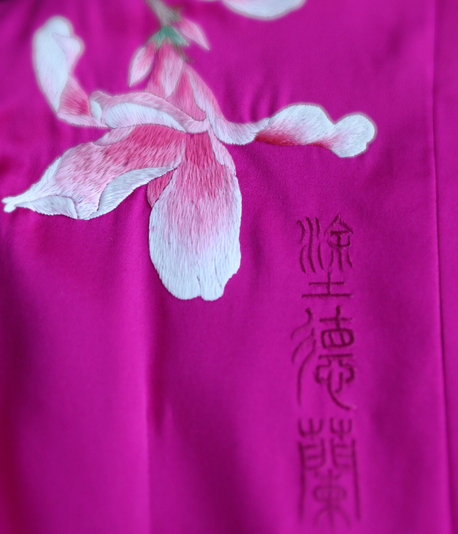 Hand-embroidered orchid and family name embroidery on a red Qipao