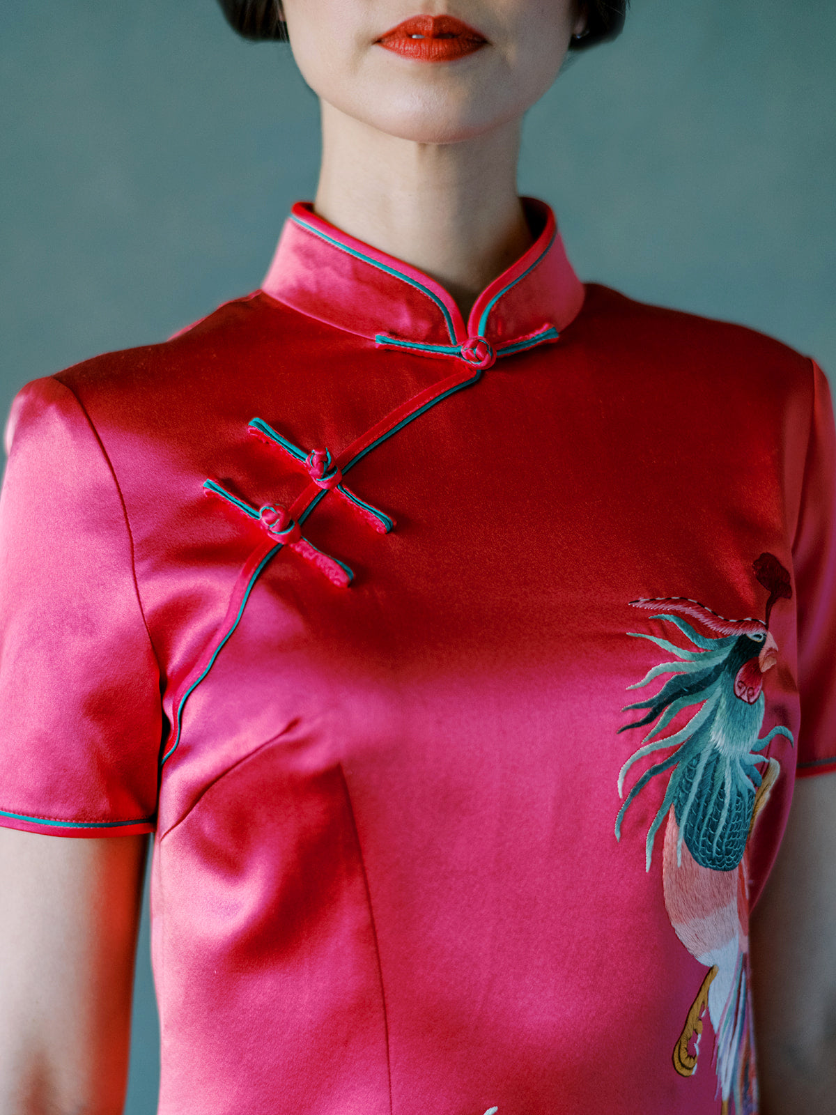 Close-up of green hand-trimmed Pankou knot on fuchsia silk Qipao