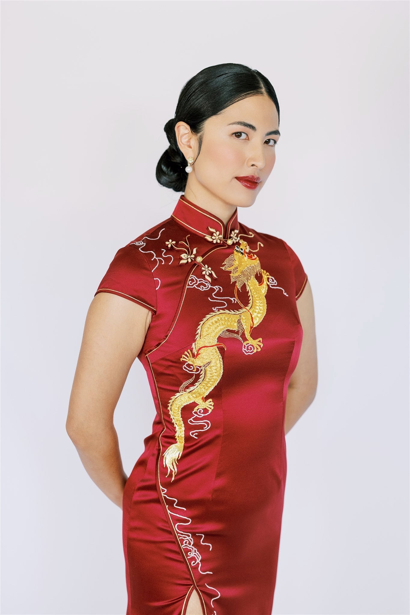 A woman wearing a modern wine red Cheongsam with gold dragon embroidery