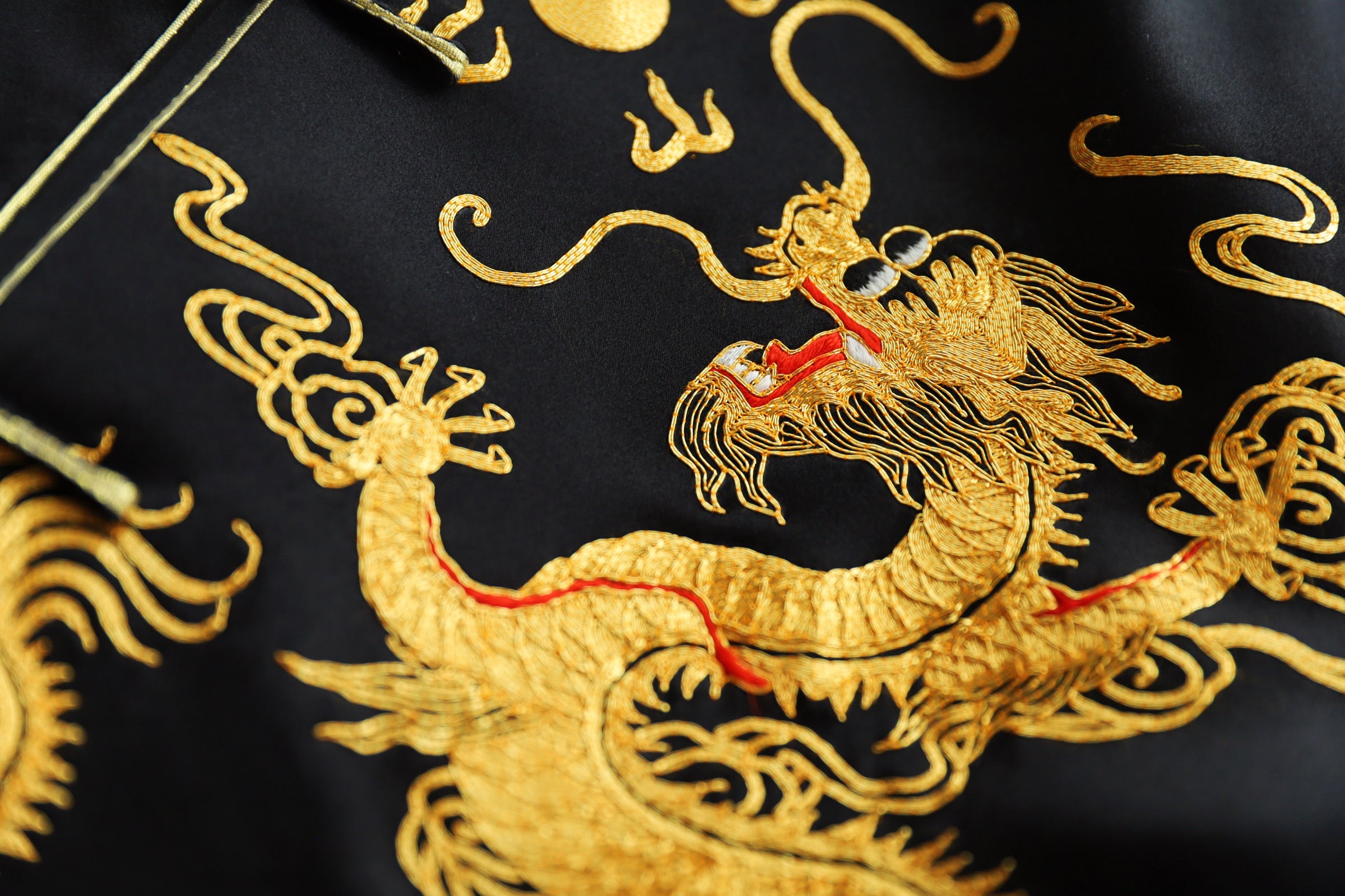 Close-up of hand-embroidery gold dragon embroidery on black silk tang suit. 