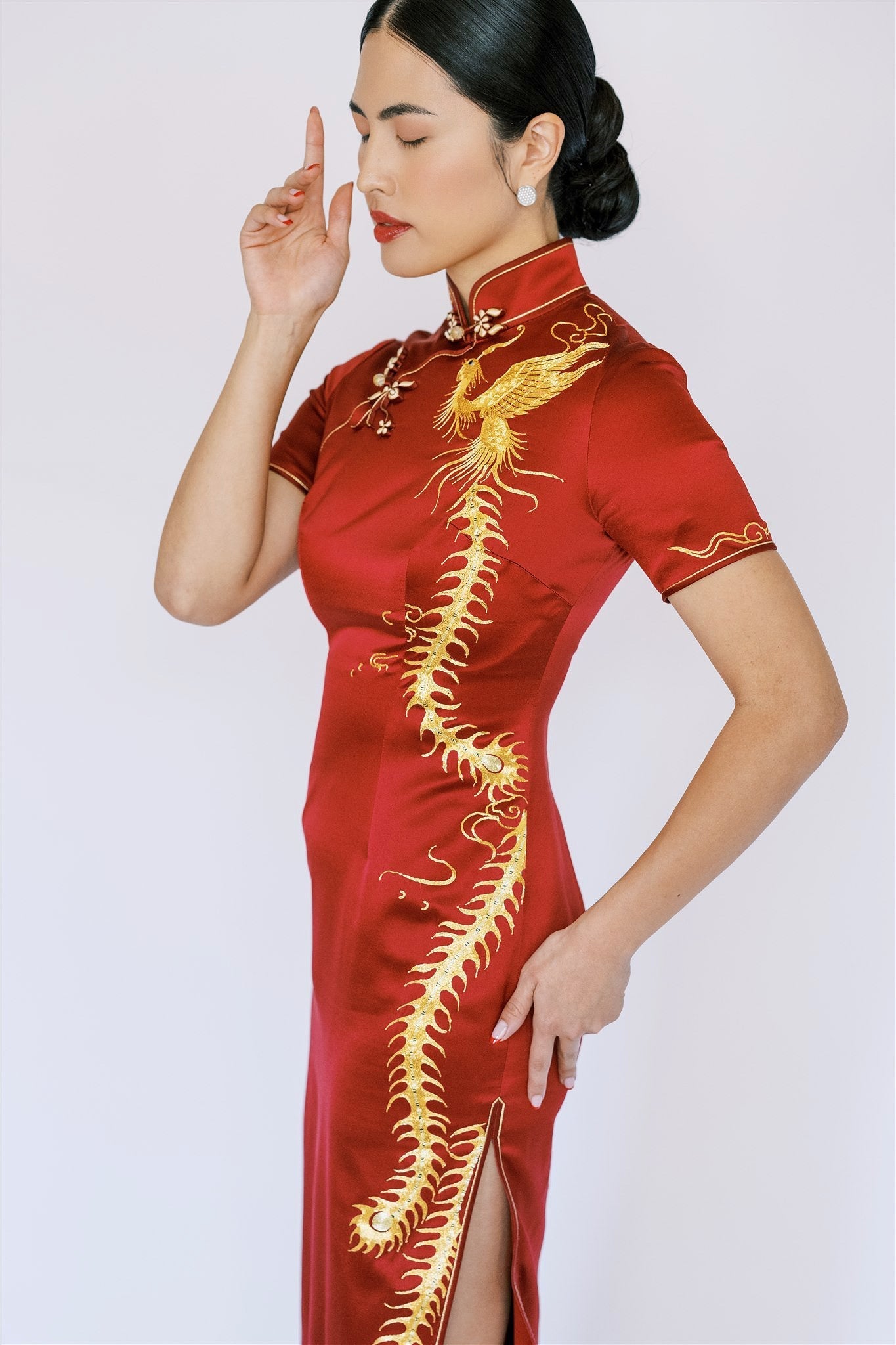 A woman wearing a wine red wedding cheongsam with gold embroidered phoenix